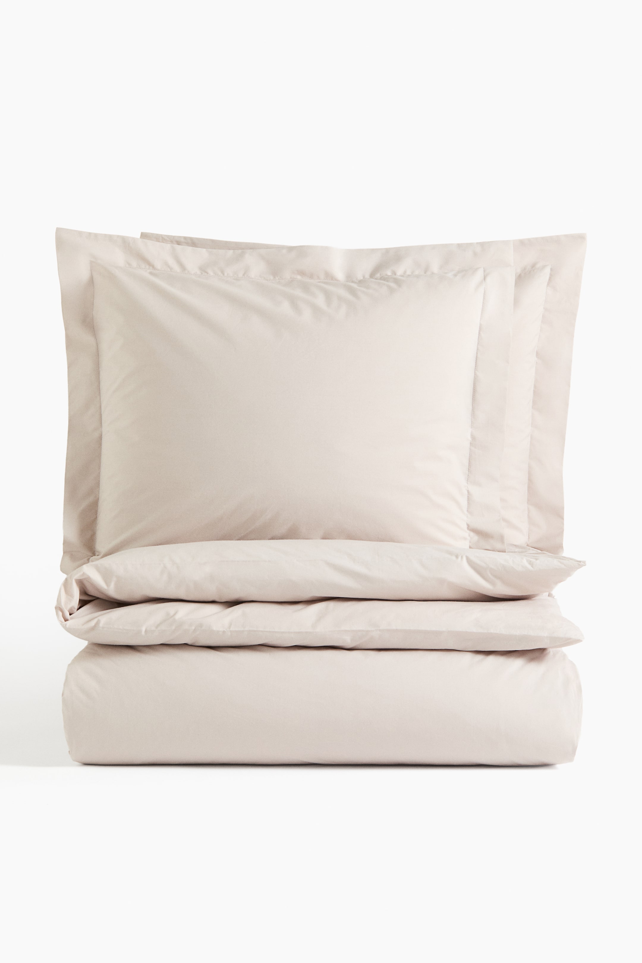 View larger image: A light beige duvet cover set is displayed at the forefront, featuring a neatly folded duvet cover at the base. Two pillowcases with a visible stitched border are stacked above, all showcasing a smooth and crisp fabric texture.