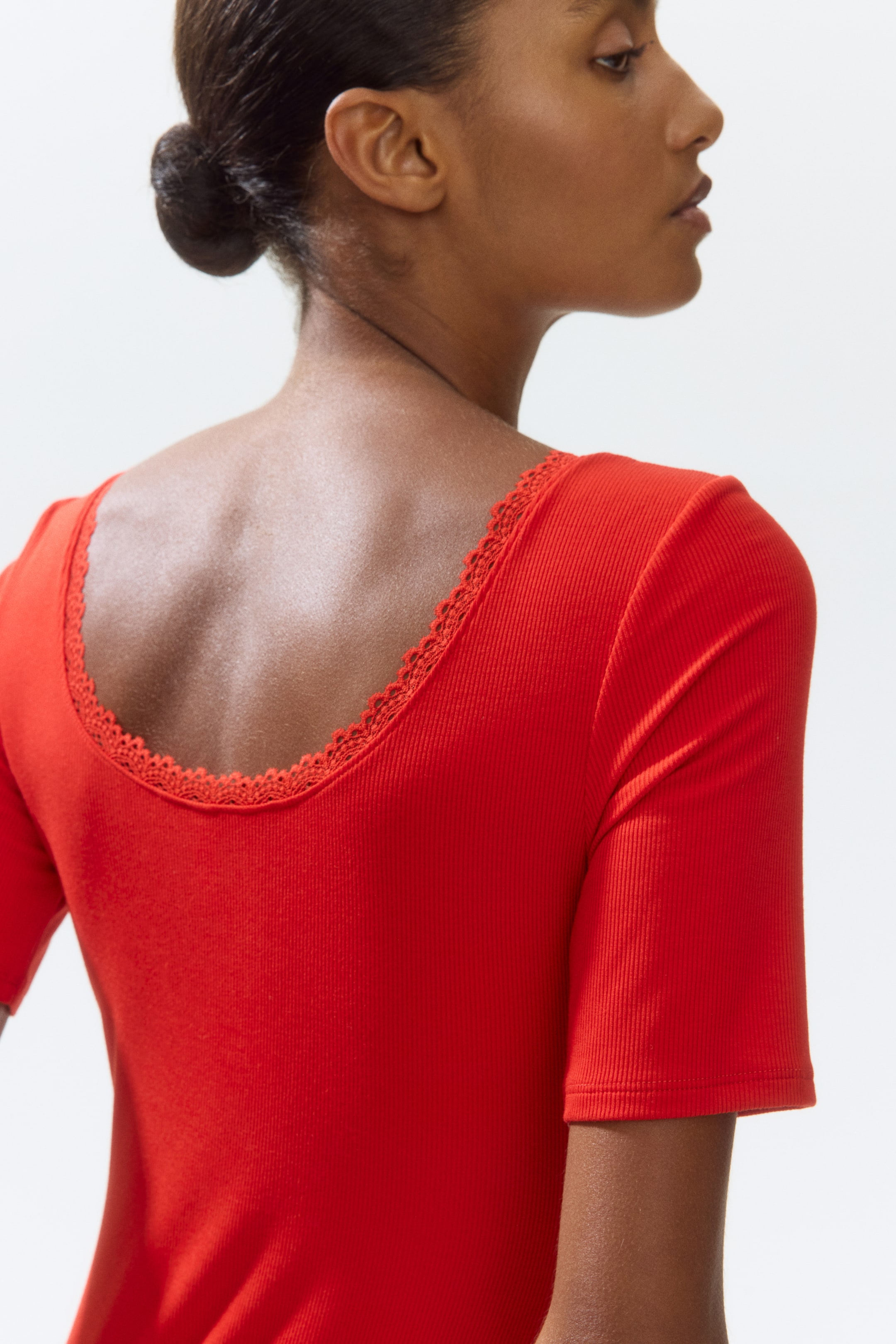 View larger image: A red ribbed top showcasing a scoop neckline adorned with delicate lace trim along the back. It also features short sleeves with a finished hem.