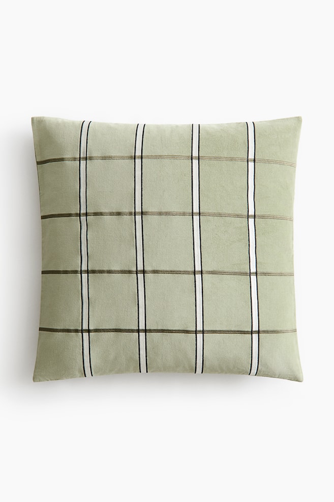 A light green cushion cover is presenting its front, made from soft cotton velvet and featuring an embroidered grid pattern of alternating dark and white vertical lines intersecting thinner dark horizontal lines. - 1