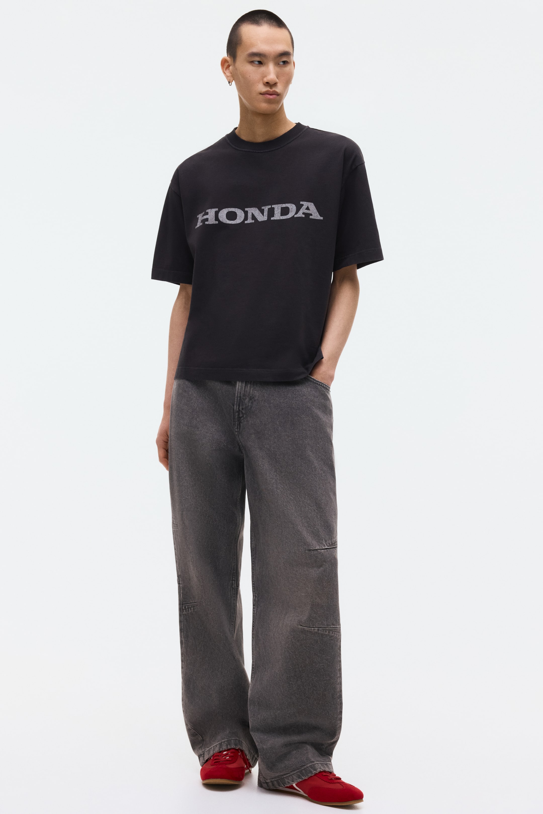 拡大画像を表示: 黒のTシャツには、胸元に目立つように配置されたグレーの「HONDA」ロゴが特徴です。ショートスリーブとクルーネックのデザインで、リラックスしたフィット感を提供します。