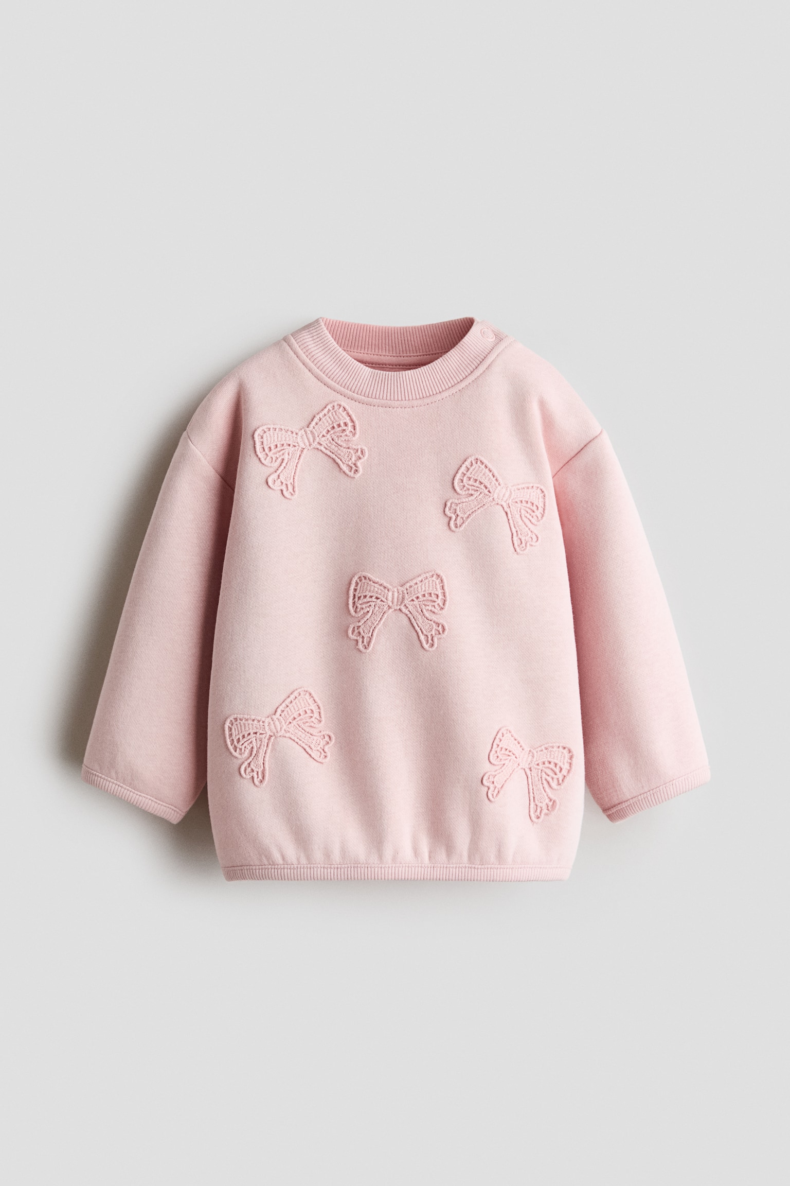 ç²ç´è² Design Detail Sweater æ­£é¢å±ç¤ºï¼æ´ä»¶æ£å¸èäºååºç¹¡è´è¶çµè£é£¾ãæ¬¾å¼æ¡ç¨é·è¢è¨­è¨ï¼è¢å£ãåé åä¸æºåçºç¾ç´é£¾éã