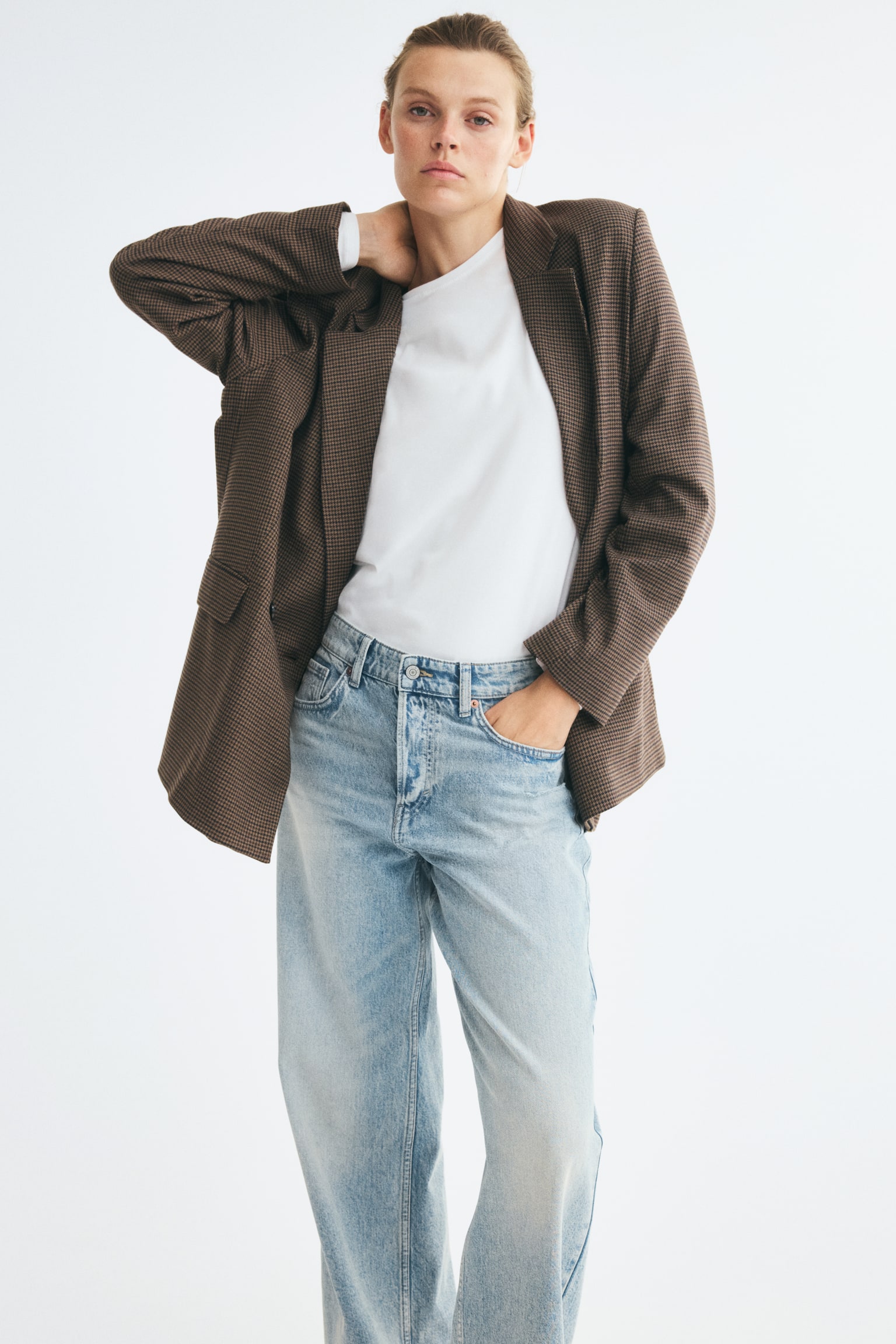 Quần jeans xanh nhạt ống rộng có một lớp giặt phai màu và mài rách ở mặt trước, hiển thị khuy cài, năm đỉa thắt lưng và túi trước có đinh tán. Gấu quần có vẻ hơi sờn. - 1