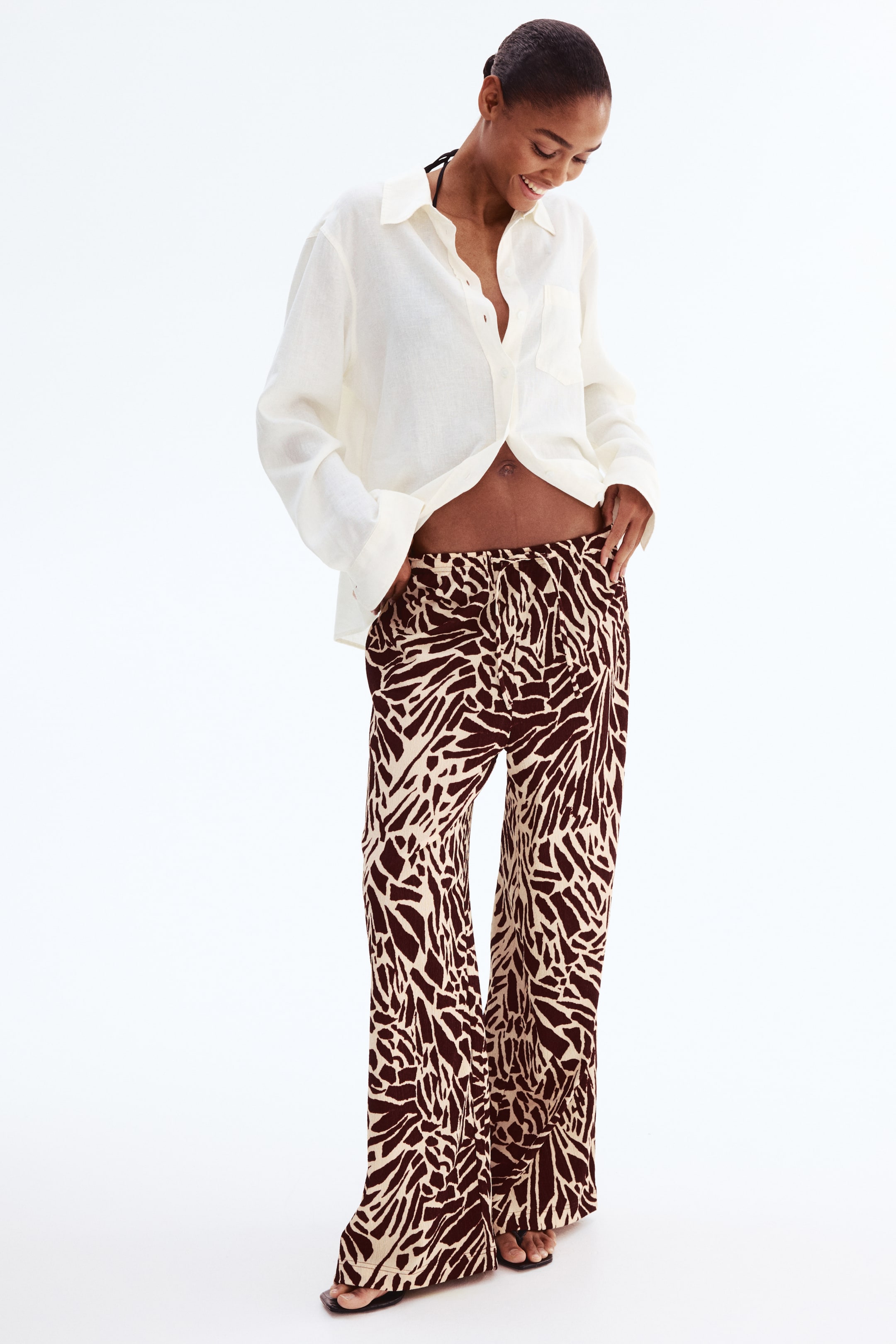 View larger image: These pants feature an abstract, irregular brown-and-cream pattern. Shown from the front, they have a relaxed, wide-leg fit, a gathered waistband, and a full-length cut.