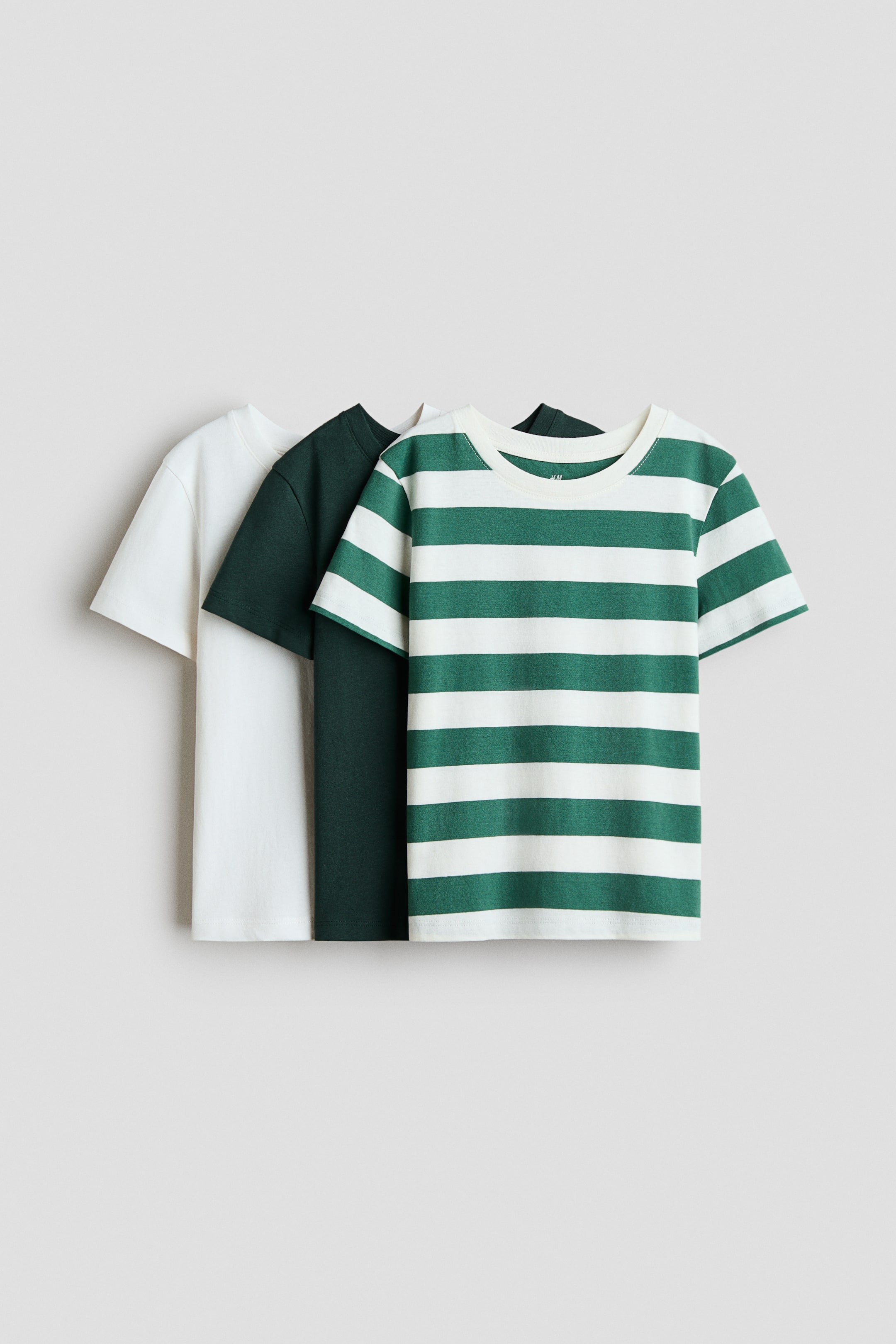 View larger image: Three T-shirts in soft cotton jersey are displayed, arranged in a slightly overlapping line and angled to the right. A cream T-shirt, a dark green T-shirt, and a green-and-cream striped T-shirt each feature a rib-trimmed round neckline and short sleeves.