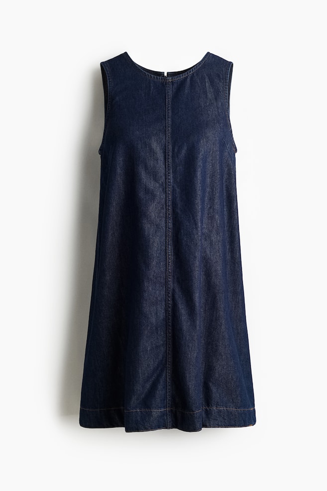 Ein ärmelloses Kleid aus dunkel gewaschenem Denim wird von vorne präsentiert, mit einem runden Halsausschnitt, einer sichtbaren vertikalen Naht, die in der Mitte verläuft, und einem geraden Saum. Ein schwarzer Reißverschluss ist am hinteren Hals sichtbar. - 1
