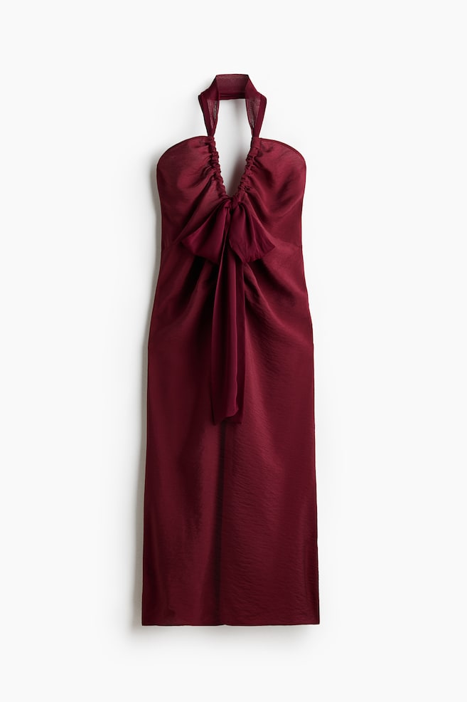 Das tiefrote Kleid besticht durch ein Neckholder-Design und ein gerafftes Oberteil an der Vorderseite. Eine große Schleife betont die Mitte der Vorderseite, und das Kleid präsentiert eine gerade Silhouette in einem glänzenden, geknitterten Stoff. - 1