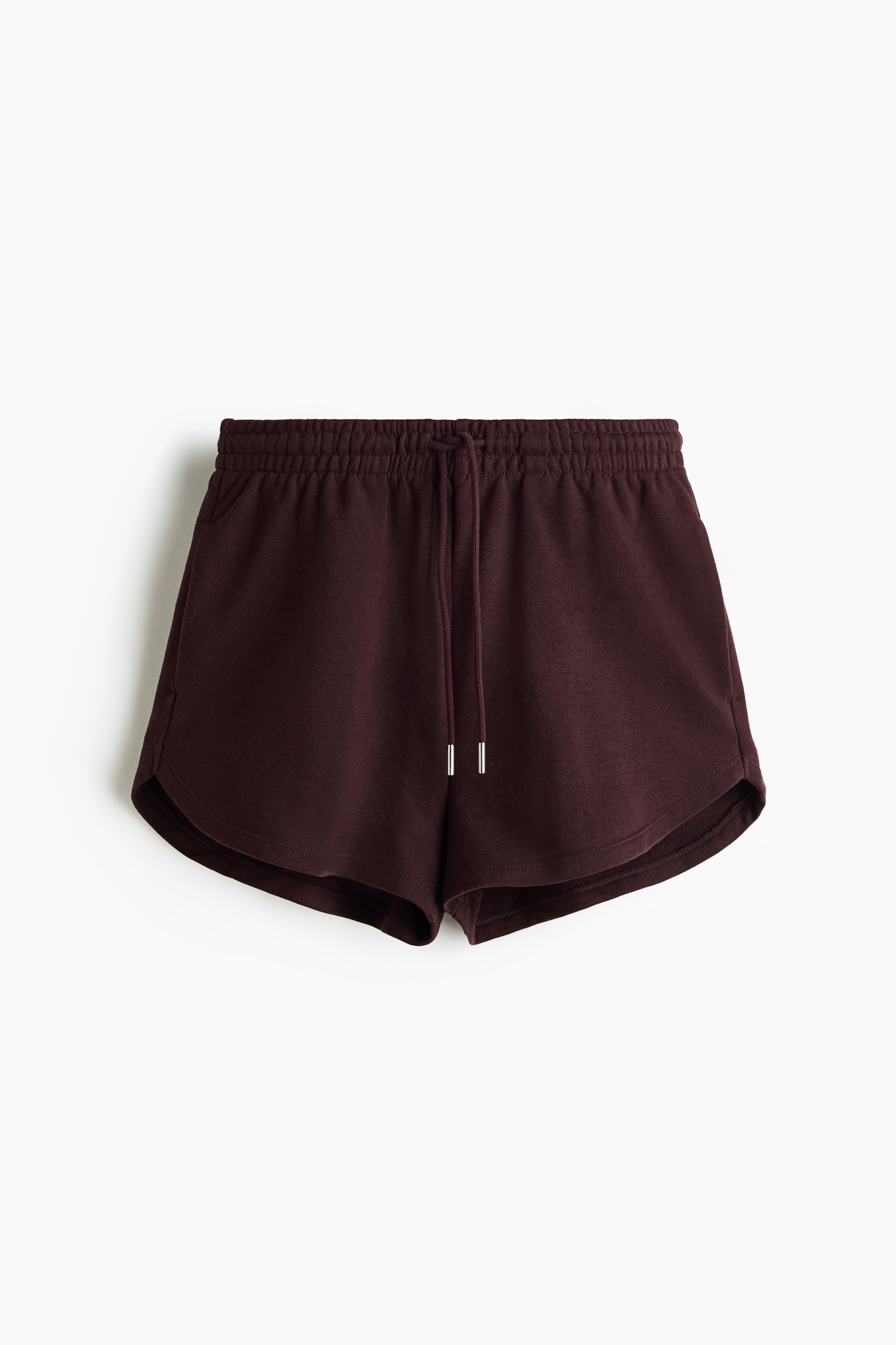 View larger image: The deep burgundy shorts are showcased from the front, highlighting a soft, sweatshirt-like fabric. They feature an elastic waistband with a visible drawstring and silver aglets, along with discreet pockets seamlessly integrated into the side seams and a curved hemline.