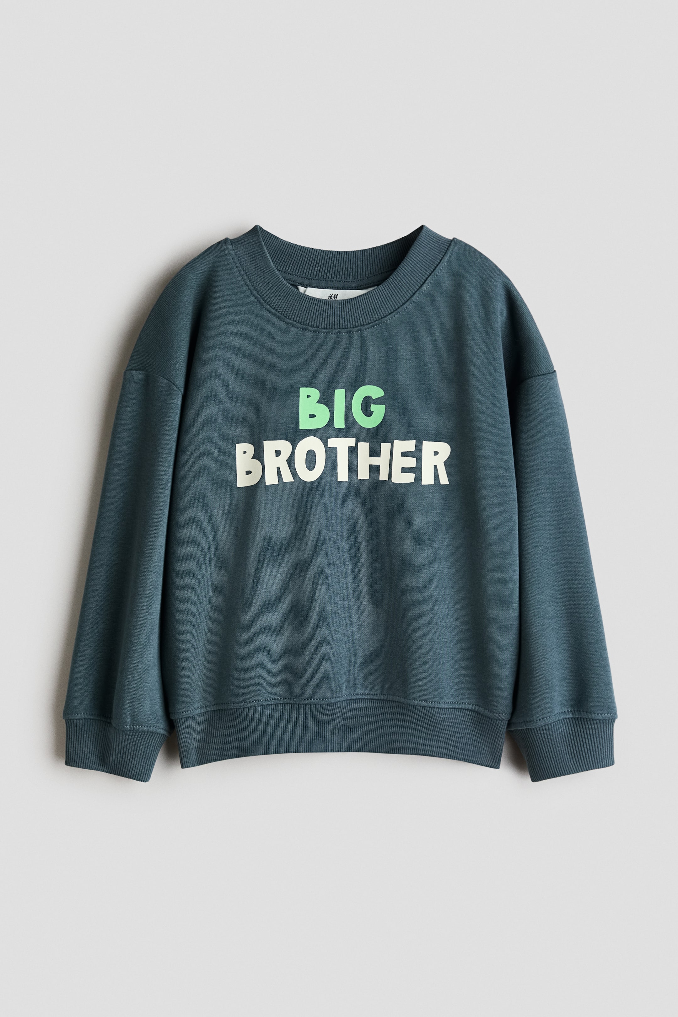 View larger image: A dark teal crew neck sweatshirt showcases a "BIG BROTHER" graphic on its front, with "BIG" in light green and "BROTHER" in off-white. It features ribbed cuffs and a ribbed hem.