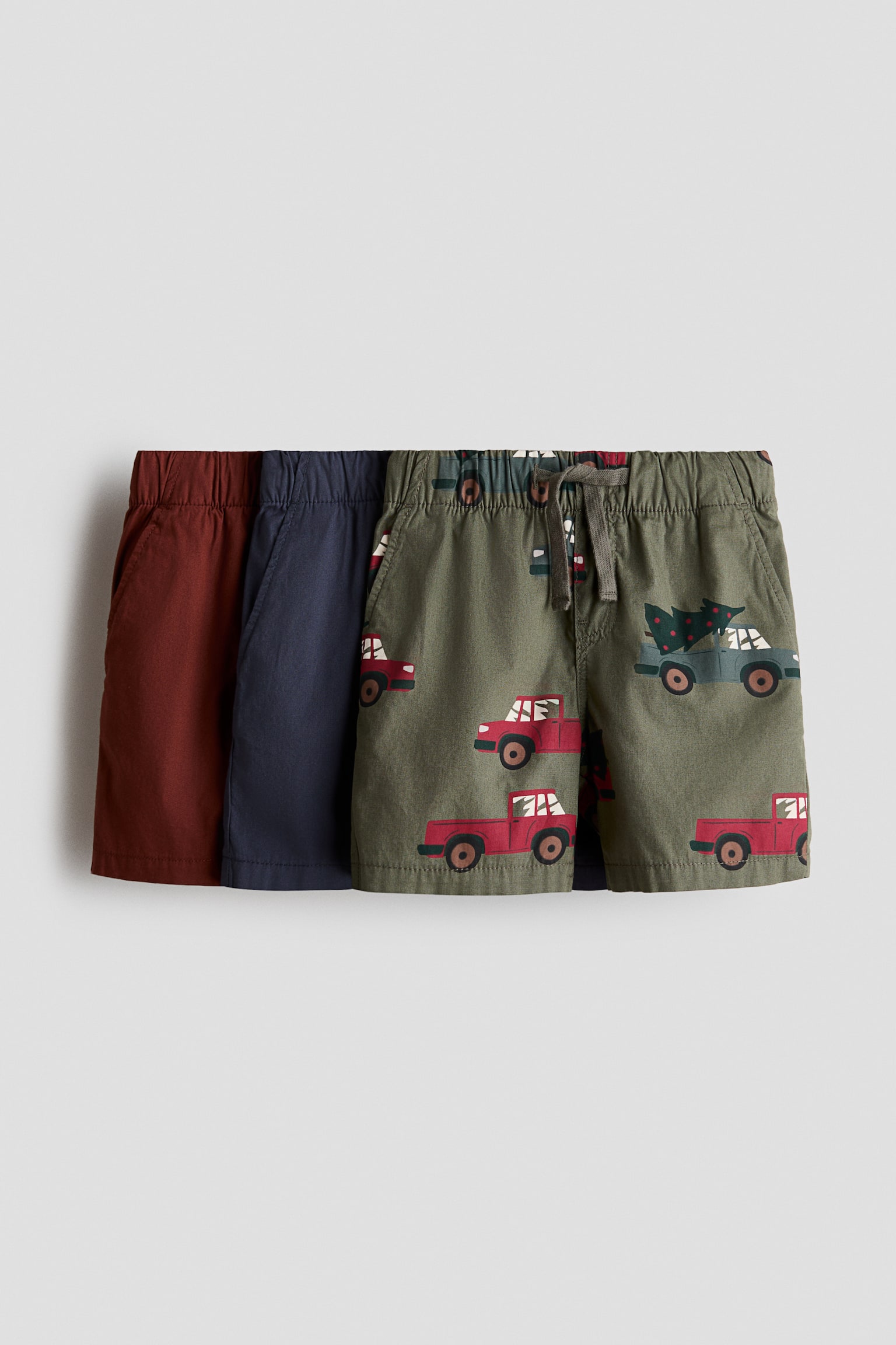 Ba cáº·p quáº§n short dá»t cotton ÄÆ°á»£c chá»¥p tá»« phÃ­a trÆ°á»c, xáº¿p chá»ng Äá» thá» hiá»n má»t cáº·p mÃ u Äá» gá» trÆ¡n, má»t cáº·p mÃ u xanh navy trÆ¡n vÃ  má»t cáº·p mÃ u xanh Ã´ liu vá»i há»a tiáº¿t toÃ n bá» lÃ  cÃ¡c xe bÃ¡n táº£i mÃ u Äá» vÃ  xanh dÆ°Æ¡ng. Quáº§n short ÄÆ°á»£c thiáº¿t káº¿ vá»i cáº¡p chun, dÃ¢y rÃºt á» cáº·p phÃ­a trÆ°á»c, khÃ³a giáº£ vÃ  tÃºi bÃªn xÃ©o.