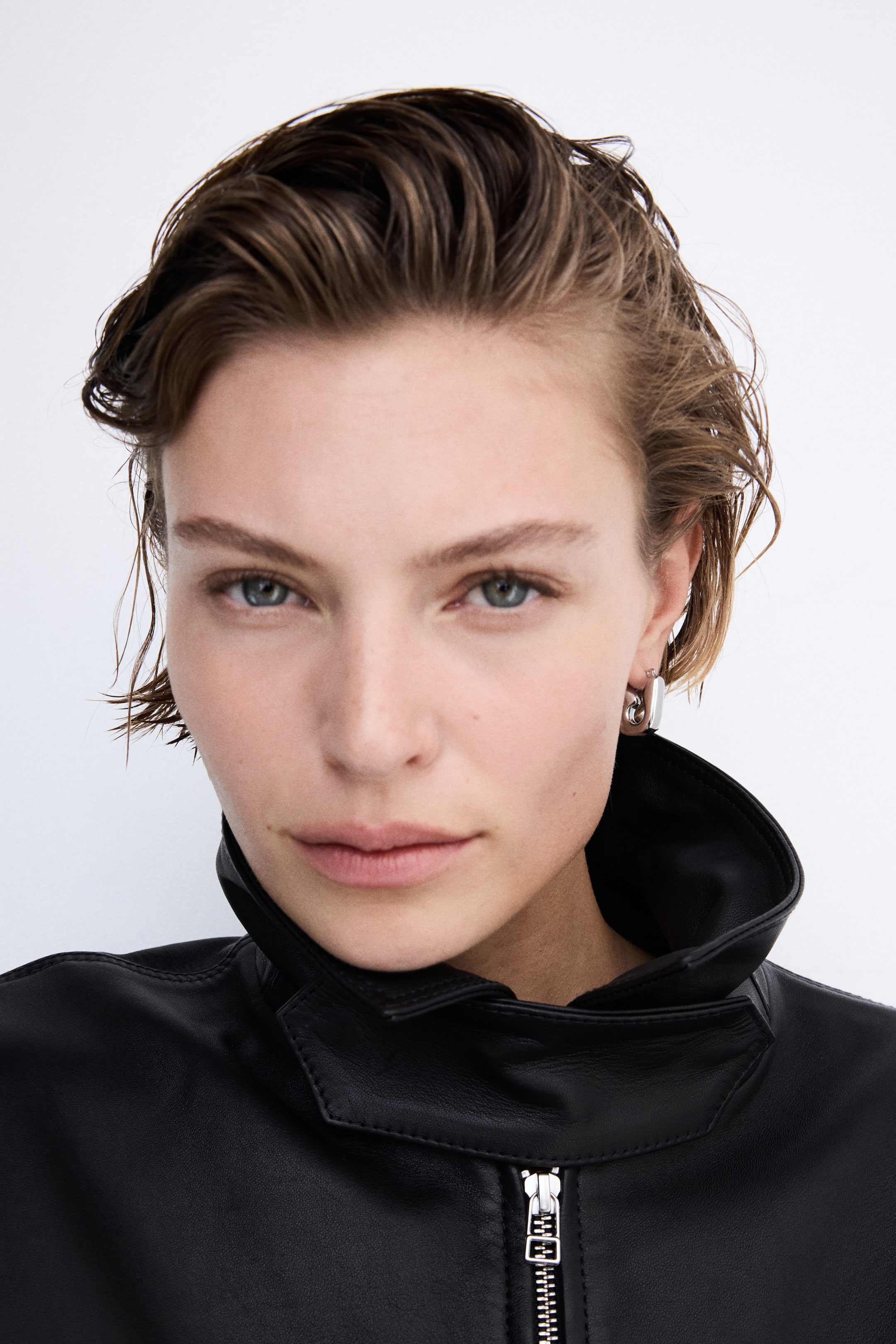 View larger image: A polished, silver-toned hoop earring featuring a squared profile inspired by a safety-pin clasp is worn on the model's ear.