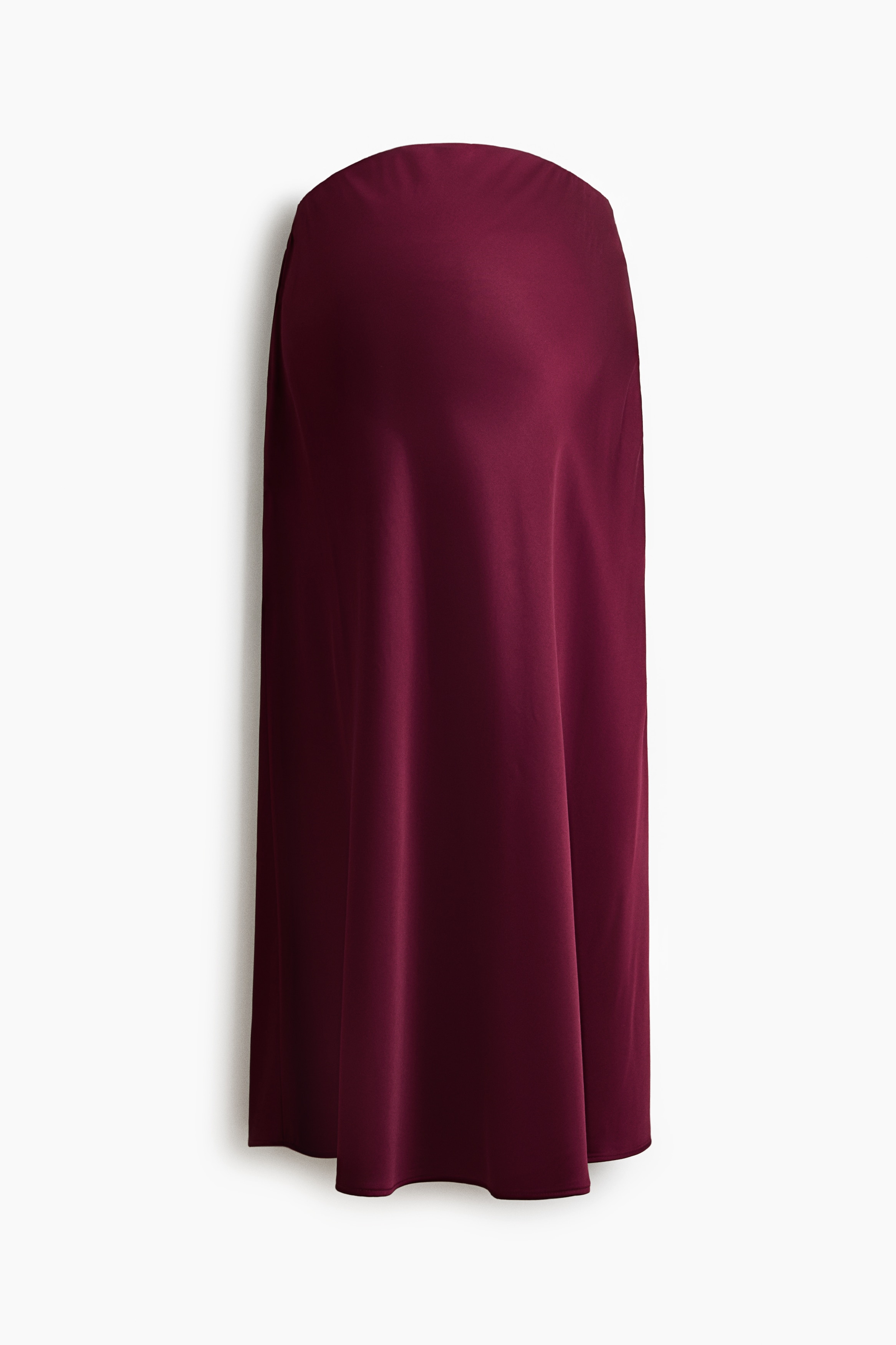 A calf-length burgundy satin skirt with a soft, fluid drape is worn by the model, who is standing and facing away from the camera. The skirt is styled with a fluffy, textured black long-sleeved sweater and light green pointed-toe heeled mules.