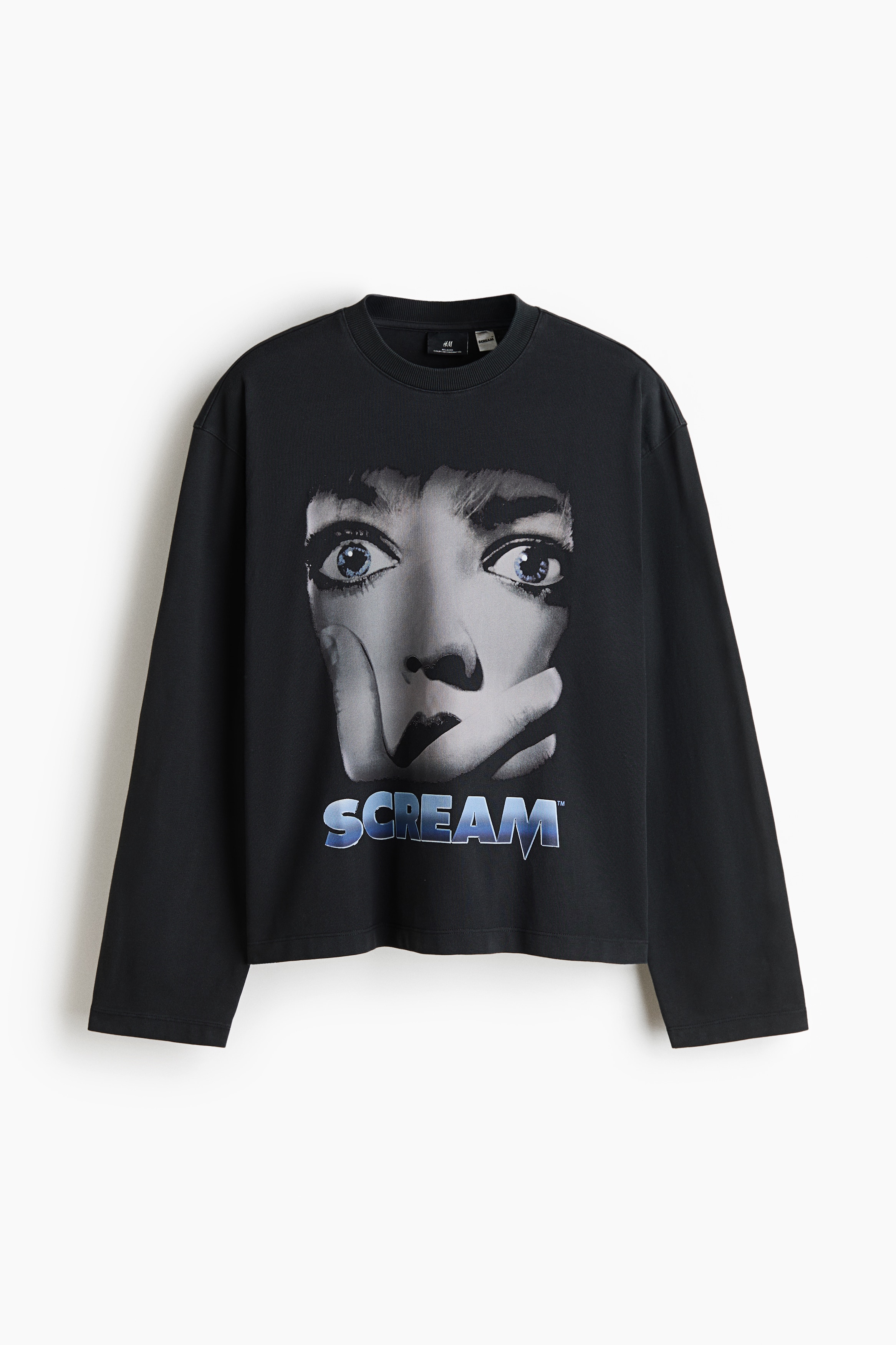 The model is wearing a dark grey, heavyweight cotton jersey long-sleeve top featuring a ribbed crew neckline, dropped shoulders and a straight-cut hem. The front of the top features a large graphic of a startled face with blue eyes above the word âSCREAMâ printed in blue and white lettering.