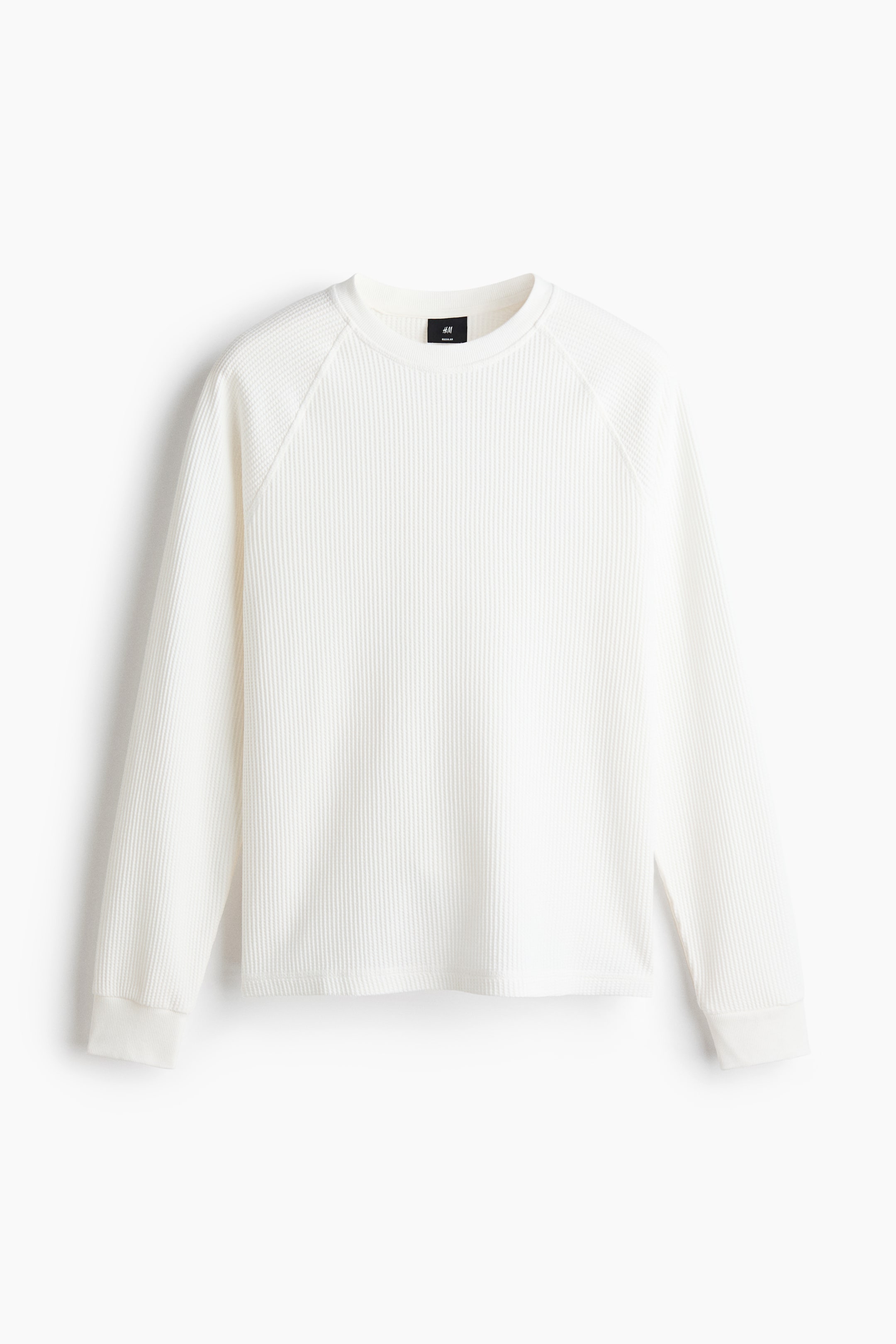 View larger image: A white long-sleeved waffle knit shirt is showcasing its front view, featuring a crew neck, raglan sleeves, and ribbed cuffs.