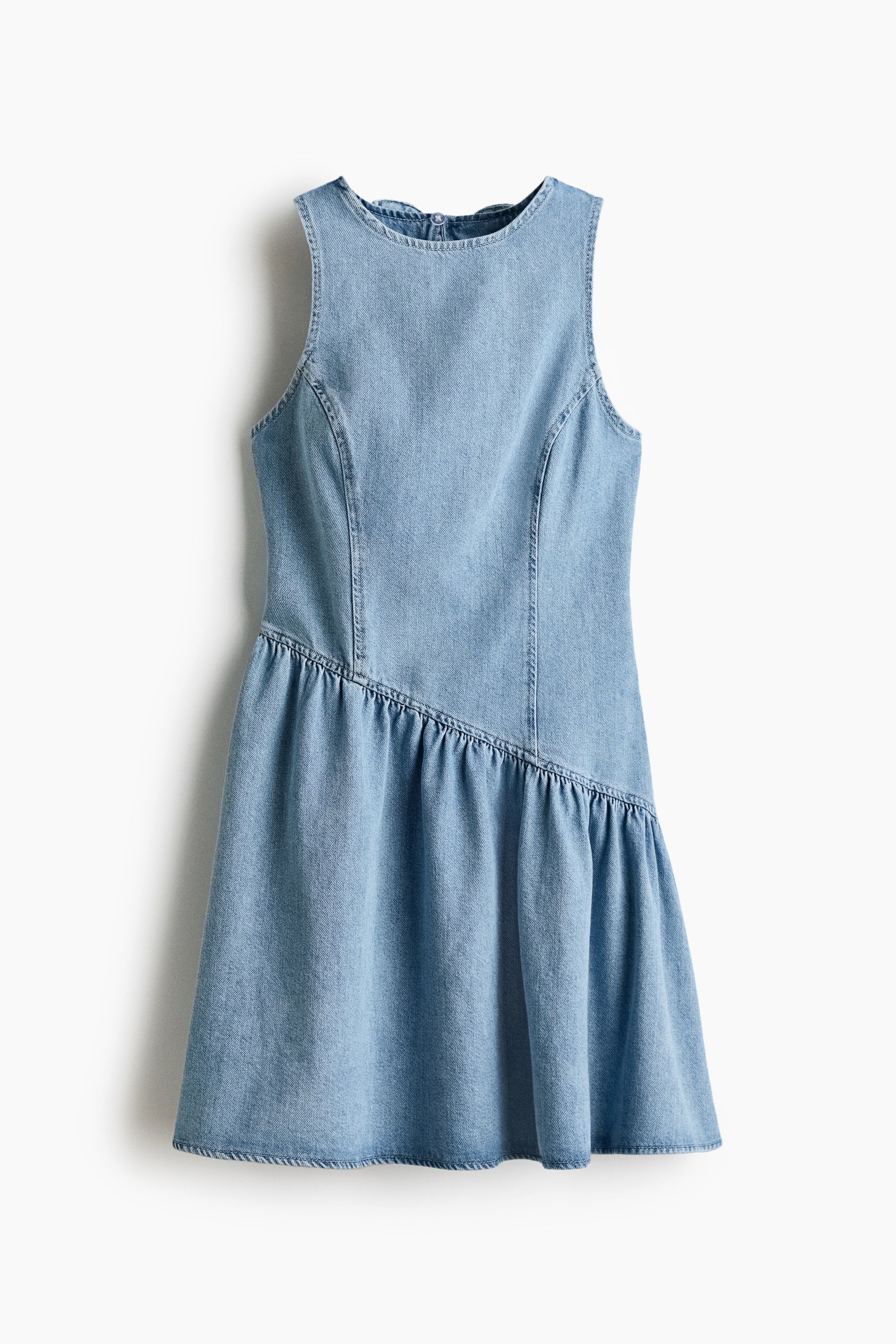 Ampliar la imagen: Un vestido de mezclilla azul claro está de frente, con un diseño sin mangas y un escote redondo. Costuras verticales moldean el corpiño. Una costura diagonal y fruncida conecta el corpiño con una falda acampanada. Un pequeño botón y un cierre de presilla son visibles en la parte superior trasera del cuello.