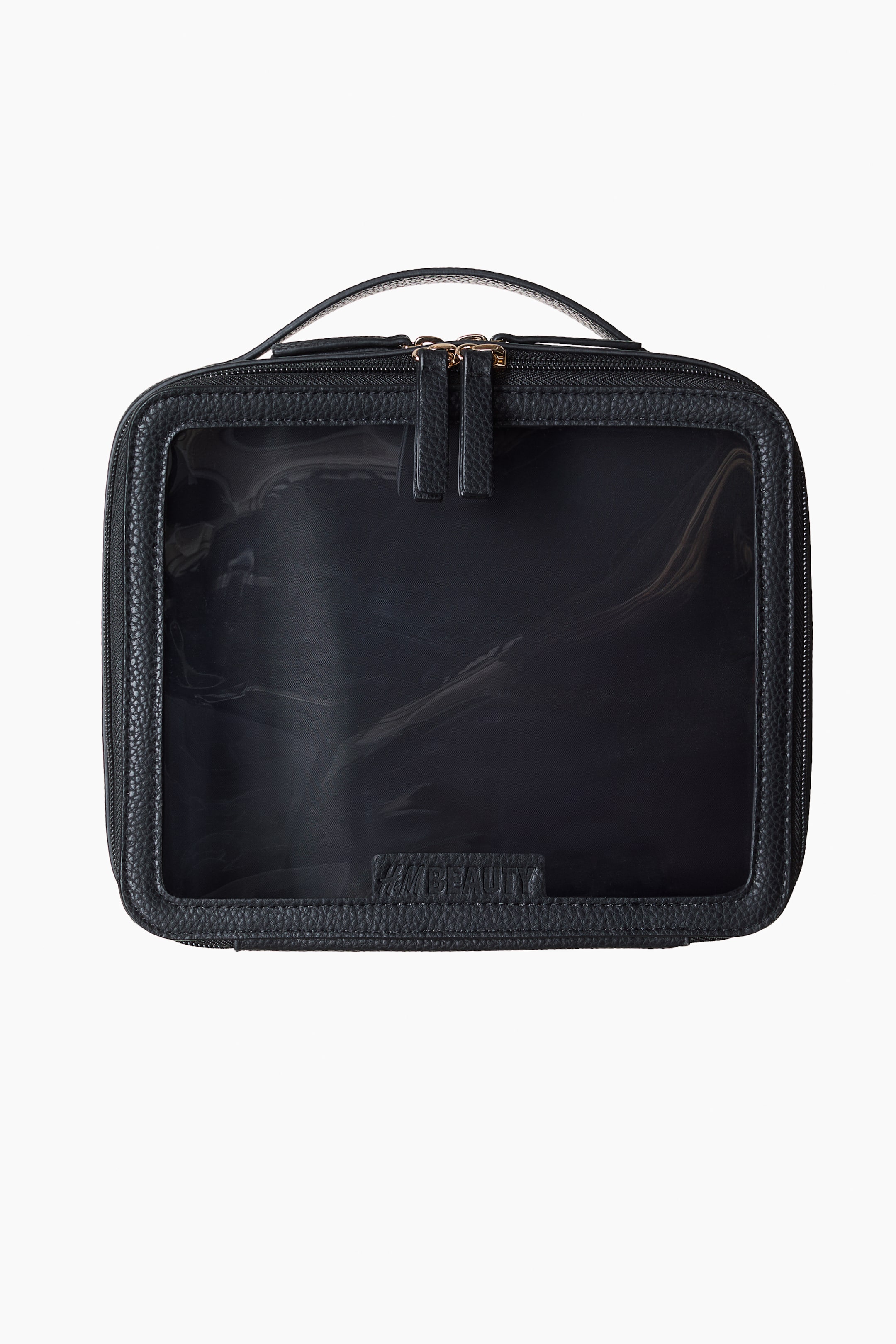 Ampliar la imagen: Una bolsa de aseo negra está orientada al FRENTE, con un exterior texturizado y un panel transparente grande en su parte frontal. Está diseñada con un asa superior y un cierre de cremallera de doble vía que recorre tres lados con tiradores en tono dorado, y "H&M BEAUTY" está grabado en una pequeña etiqueta en la parte inferior del panel transparente.