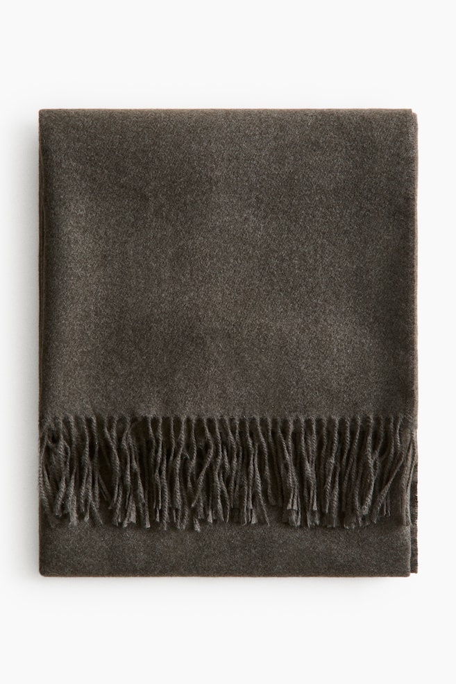 A dark brown blanket is folded neatly into a rectangular shape, featuring a soft, brushed texture and a fringe along one side. - 1