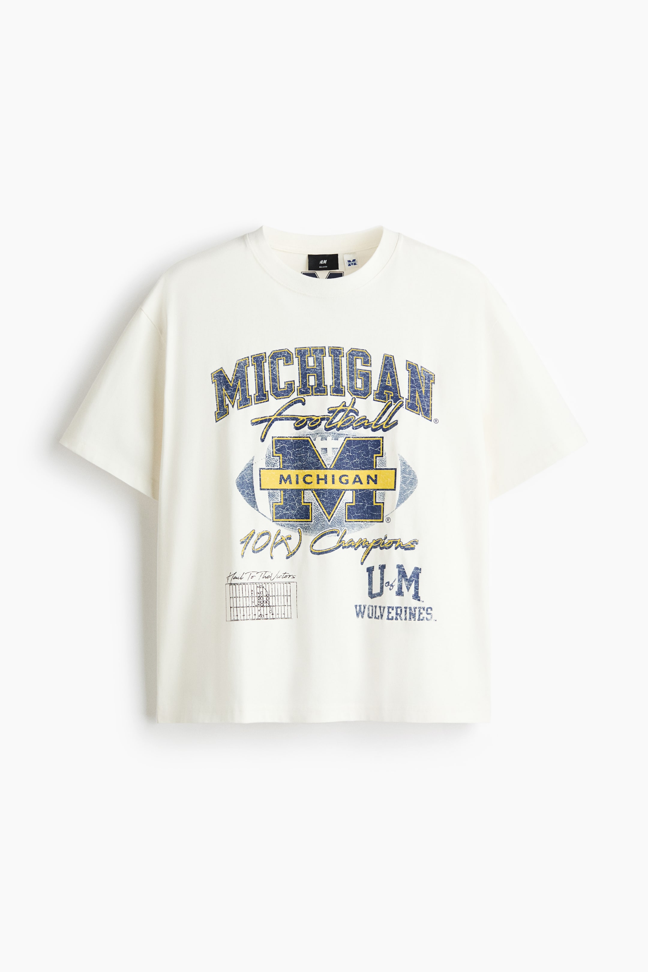 View larger image: A cream T-shirt features a large, distressed blue-and-yellow 'MICHIGAN FOOTBALL' graphic on the front, which incorporates a football motif, the letter 'M' and the text '10K Champions'. It is designed with a round neckline, narrow trim and dropped shoulders, offering a loose fit.