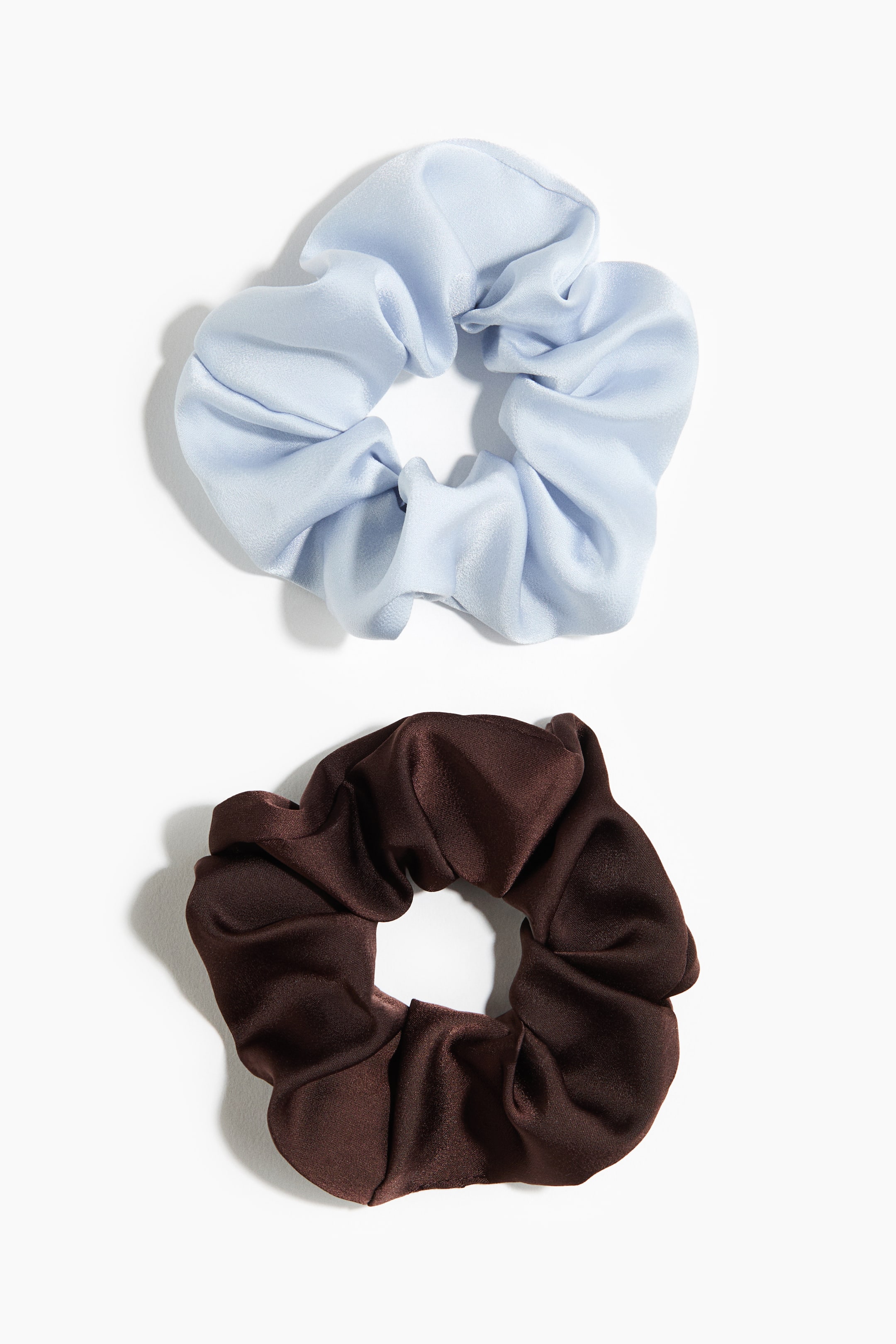 Ampliar la imagen: Grandes scrunchies elásticos en tela tejida con un ligero brillo son visibles. Un scrunchie es de color azul claro, y el otro es marrón oscuro, ambos exhiben una apariencia completa y recogida.