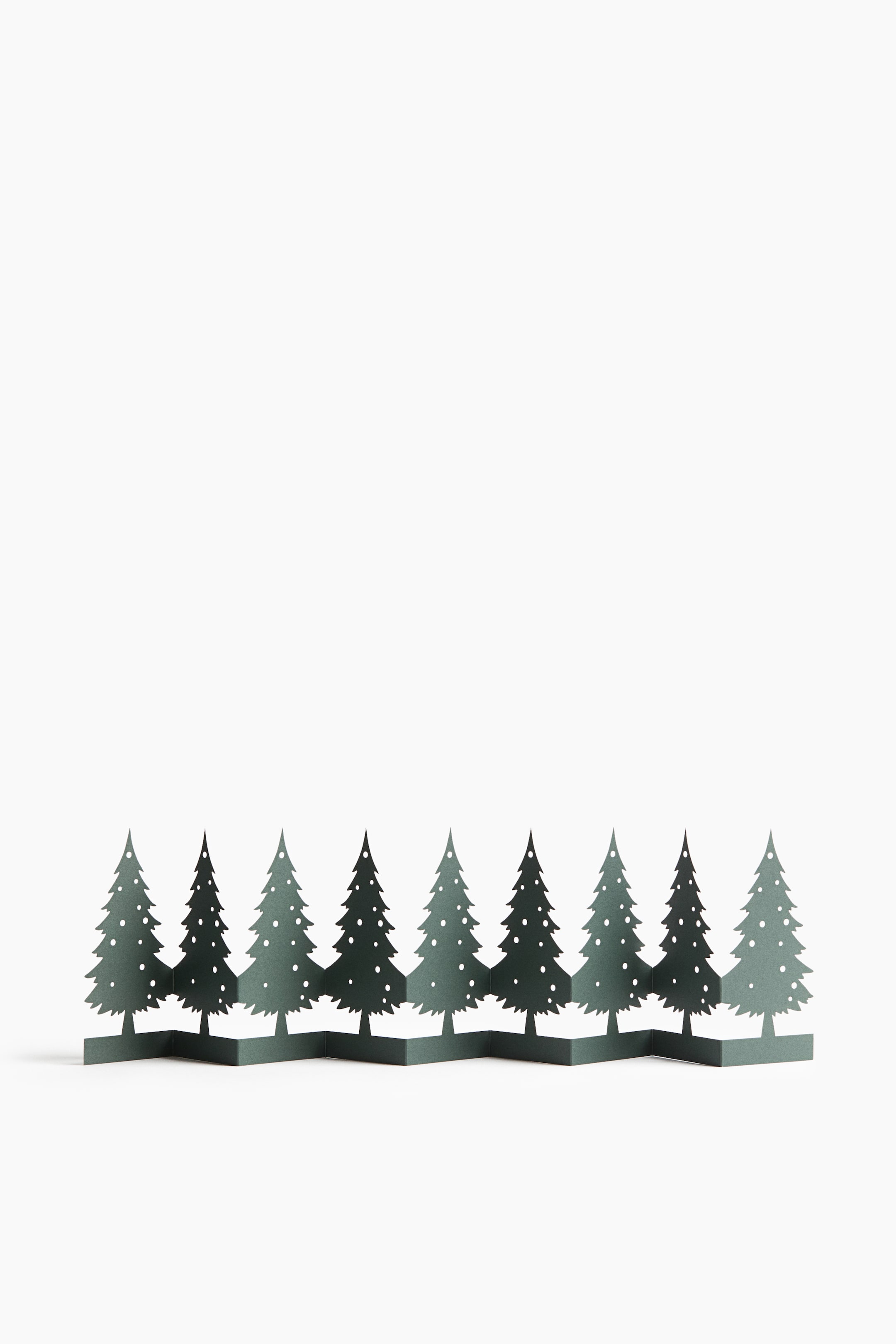 View larger image: A dark green decorative stand featuring a row of nine stylized pine trees with small circular cutouts is standing upright in an accordion-style zigzag fold, shown from the front.