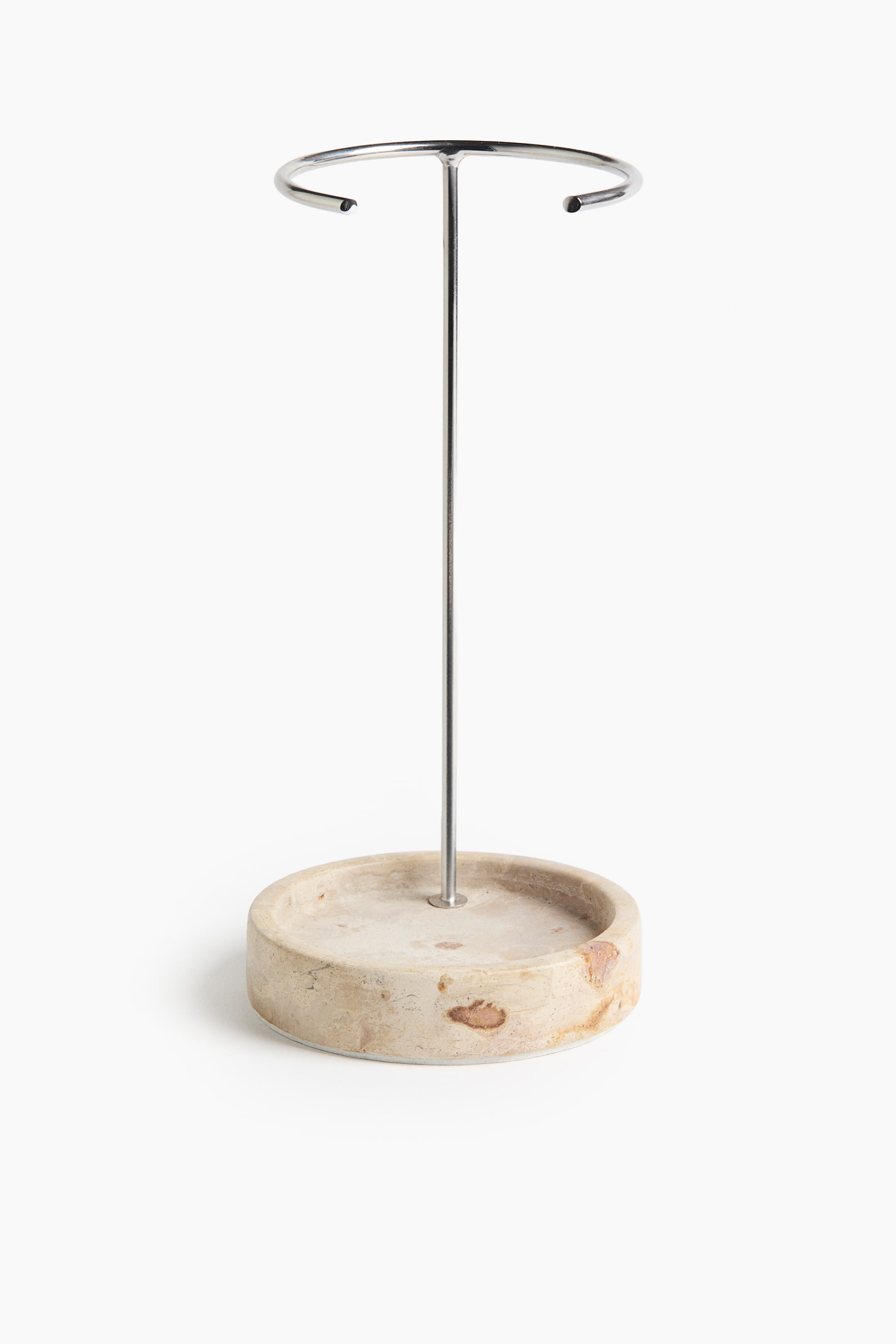 View larger image: The jewellery stand showcases a sleek silver-toned metal rod, crowned by an open circular bar at the top. It elegantly rises from a circular marble base, exhibiting natural light and dark variations.