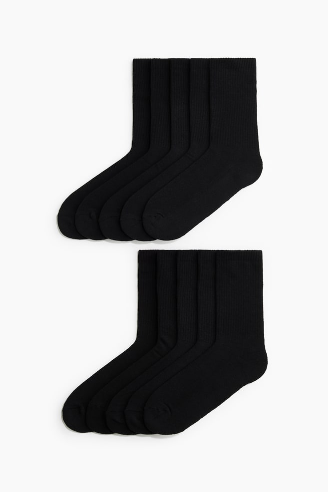 Black crew socks are displayed in two stacked, overlapping groups of five, showcasing their side-profile design. The socks feature a ribbed texture along the leg and cuff, transitioning into a smooth knit foot. - 1