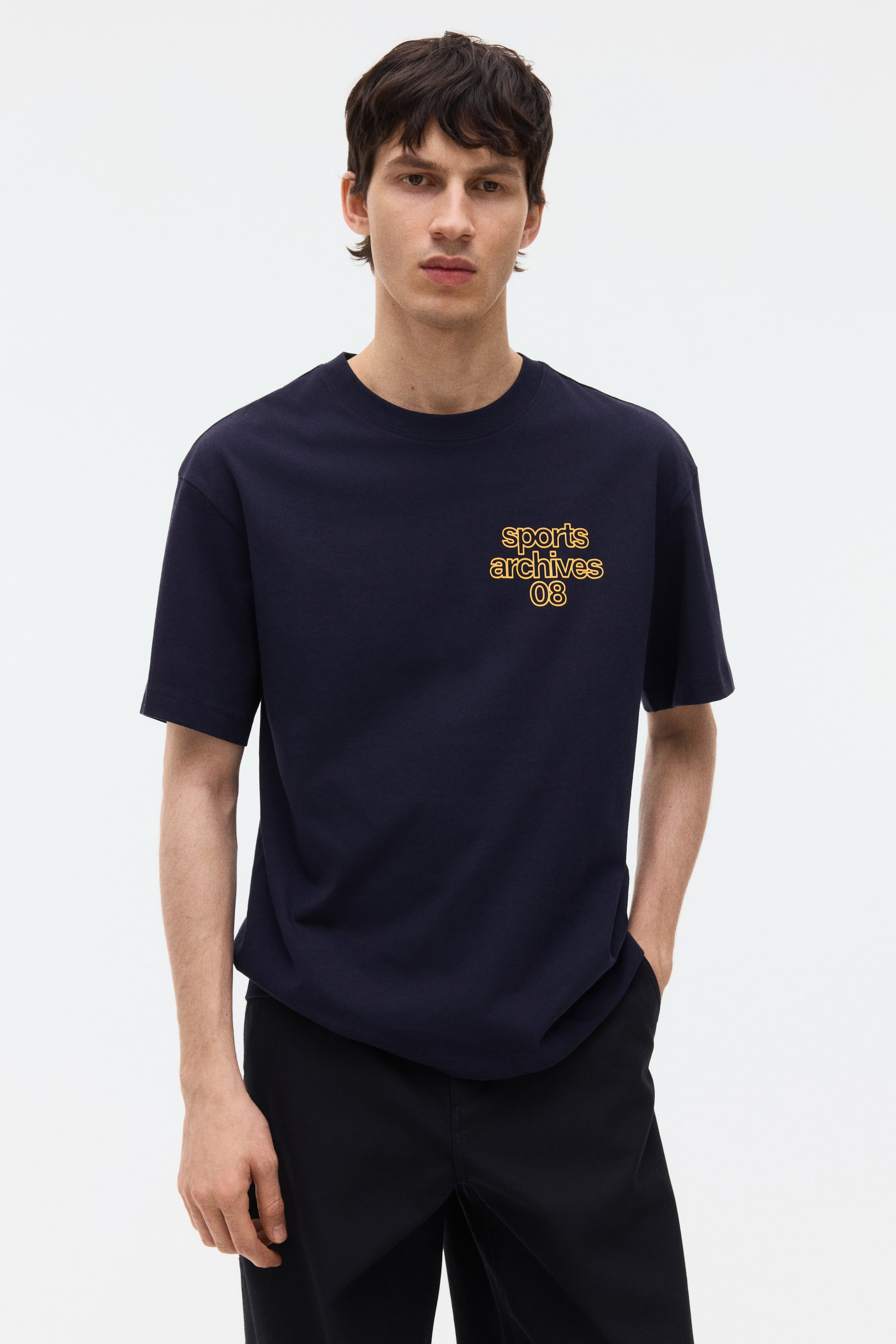 View larger image: A navy blue t-shirt featuring a relaxed fit, a crew neck, and short sleeves, with yellow text reading "sports archives 08" printed on its front chest.