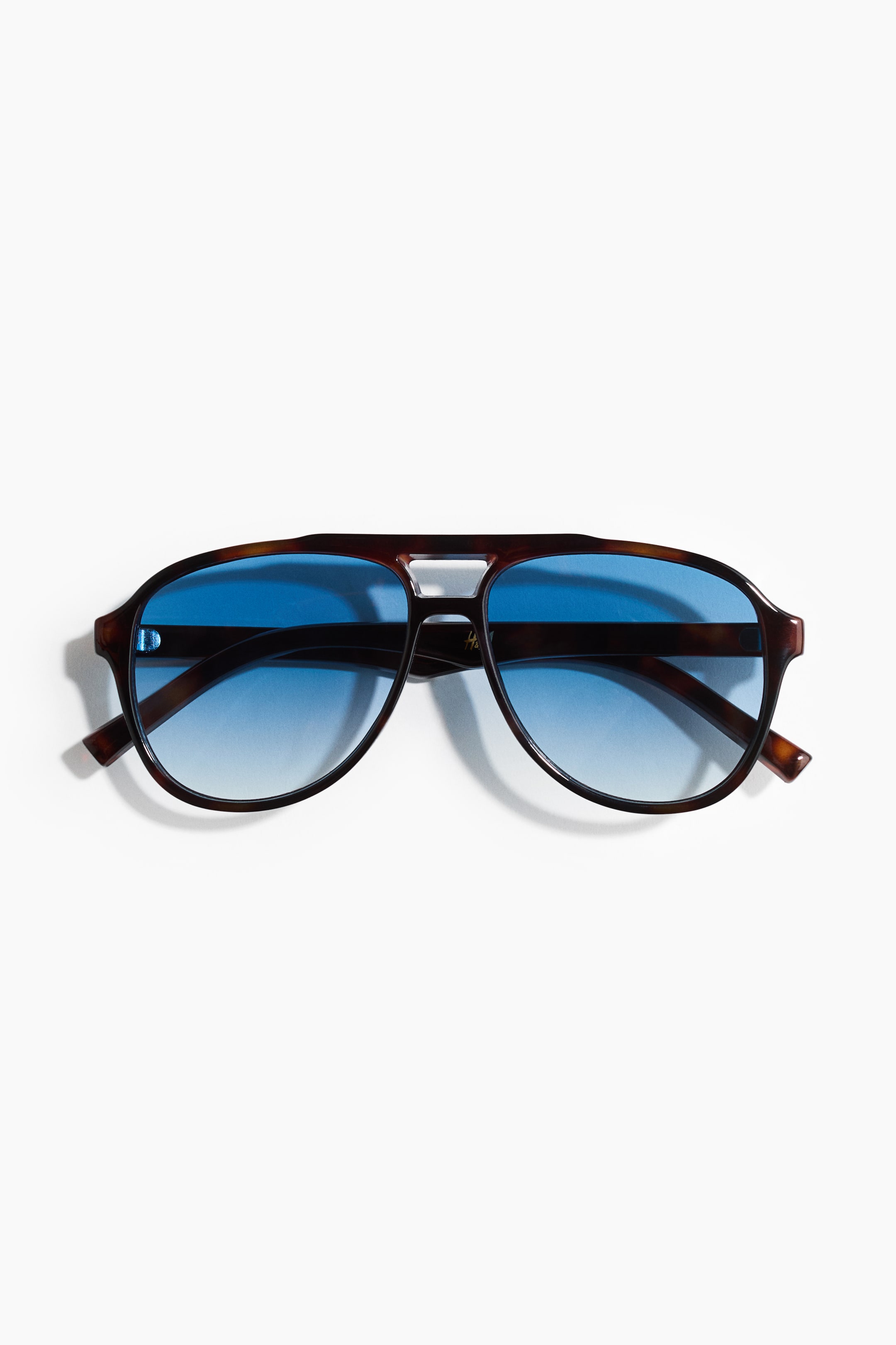 View larger image: Aviator-style sunglasses are displayed front-facing, showcasing tortoiseshell plastic frames. They come equipped with blue gradient tinted, UV-protective lenses.