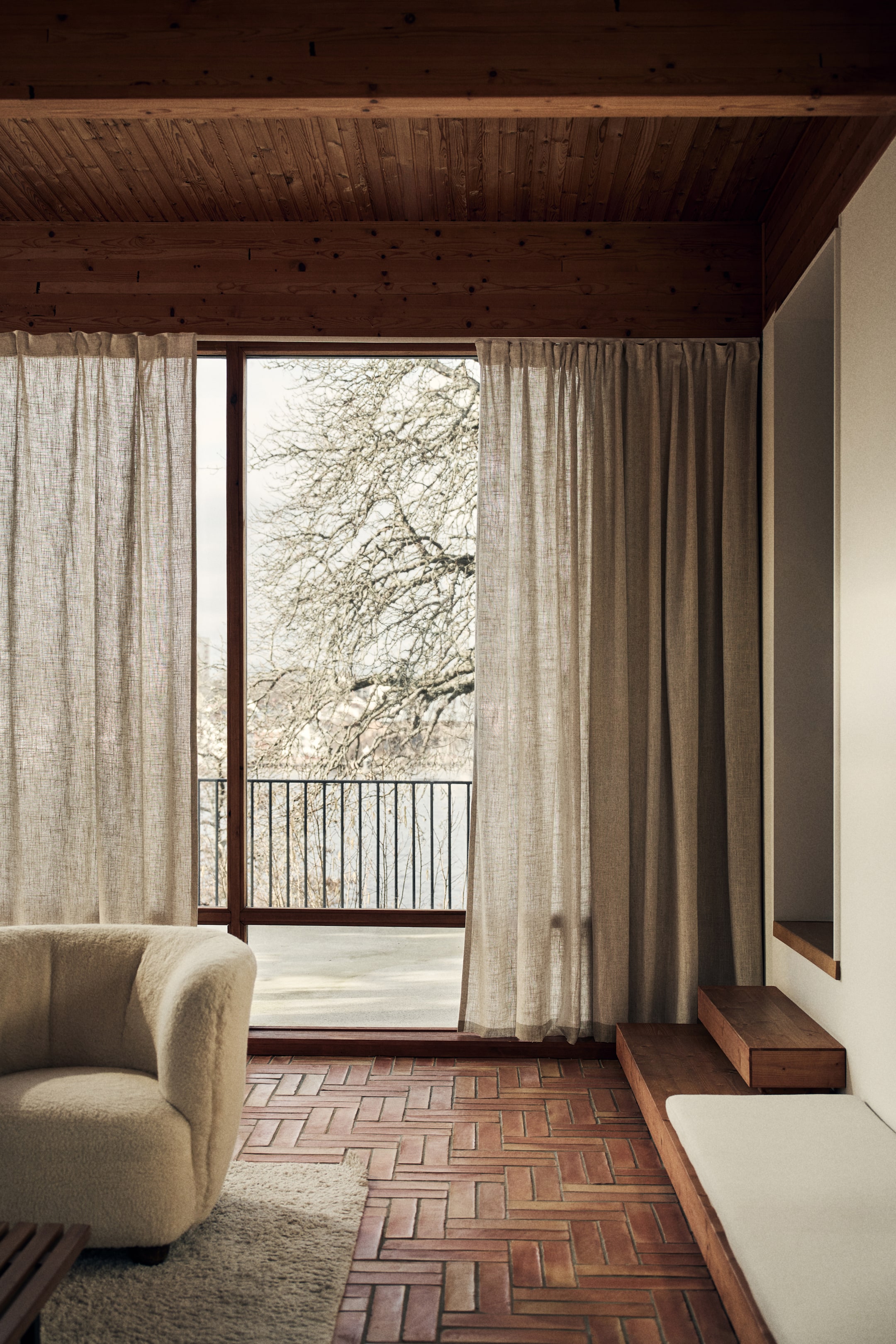 Ver imagen más grande: Una cortina extra larga y ancha, confeccionada con un tejido de mezcla de lino de caída pesada en un tono natural, cuelga de un cabezal multifuncional fruncido, formando suaves pliegues verticales.