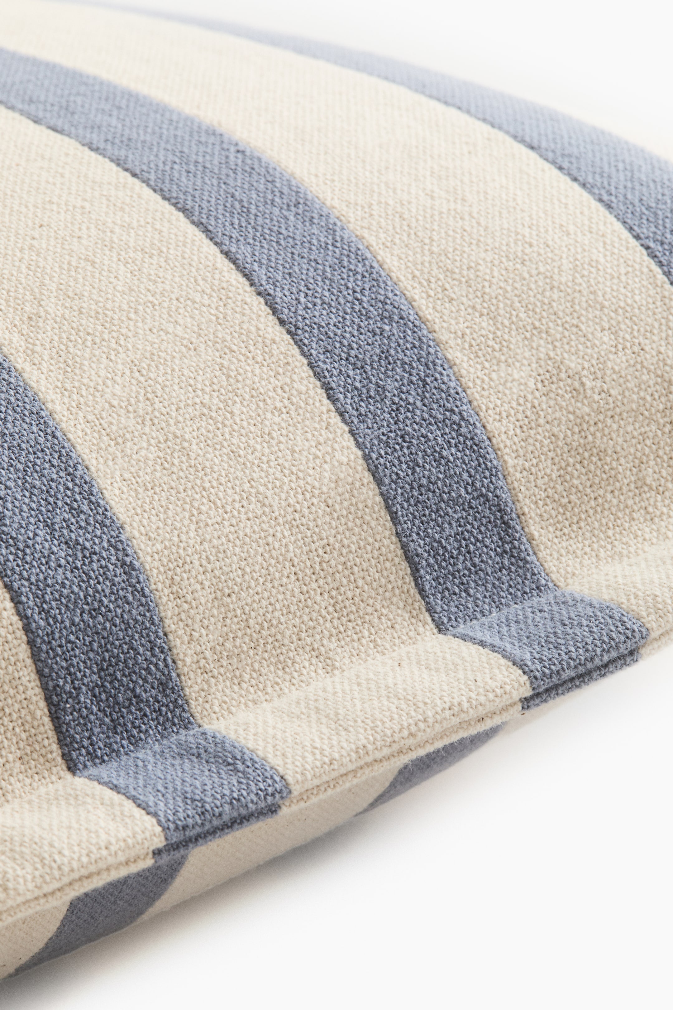 Visualizza l'immagine ingrandita: Un cuscino caratterizzato da ampie strisce alternate di beige chiaro e blu tenue. Il tessuto intrecciato presenta una texture grezza, con le strisce che corrono diagonalmente sulla sua superficie.