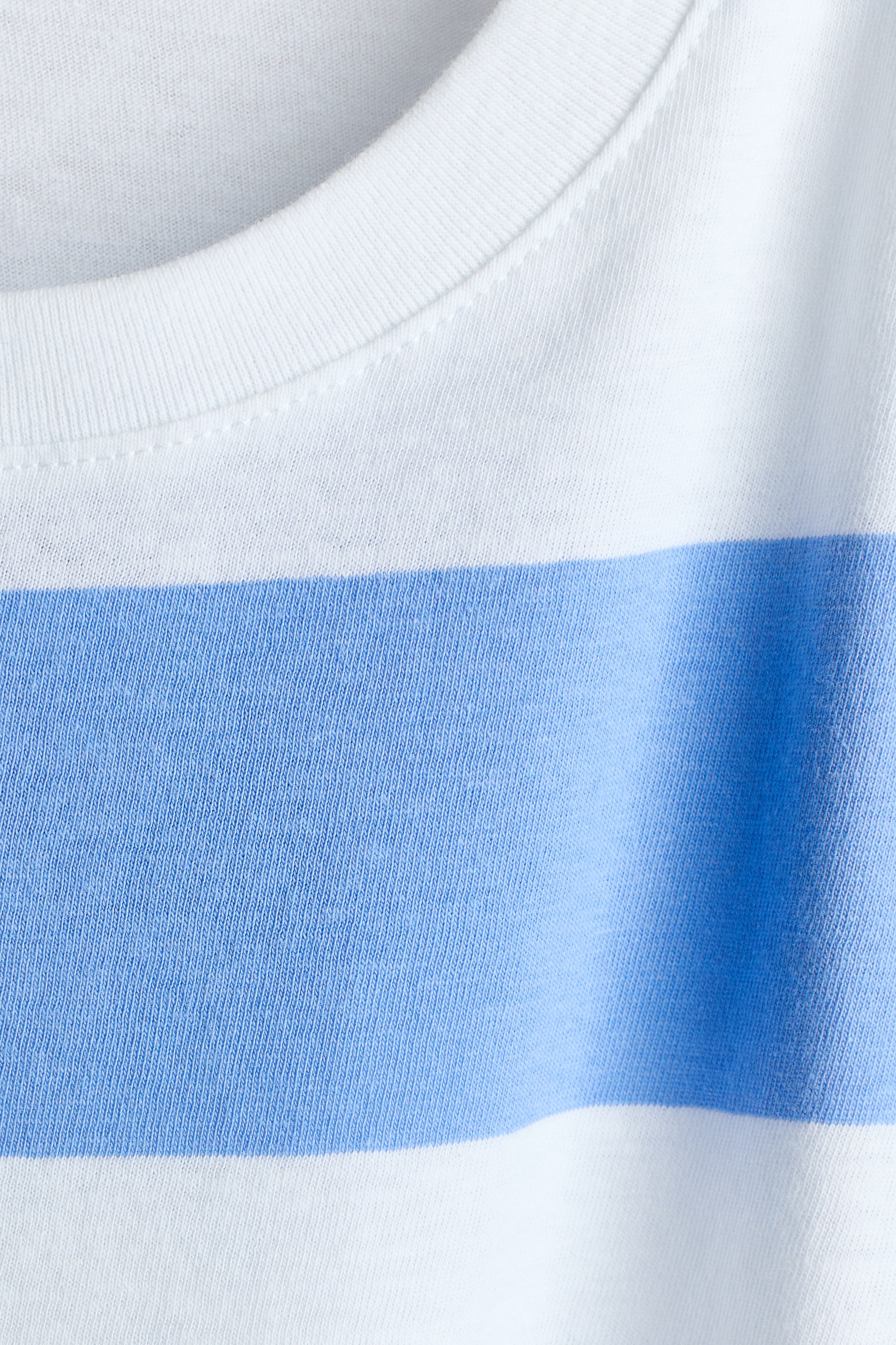 Ampliar la imagen: Camiseta de suave algodón jersey con un patrón de rayas horizontales blancas y azul claro en el frente. Un cuello redondo acanalado con costuras prolijas es visible en la parte superior.