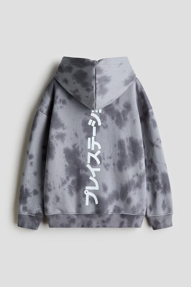 A loose-fit hoodie with a grey and dark grey tie-dye pattern is shown from the back, featuring a lined hood, dropped shoulders, and ribbed cuffs and hem. A vertical print of white Japanese characters is running down the center of the back. - 1
