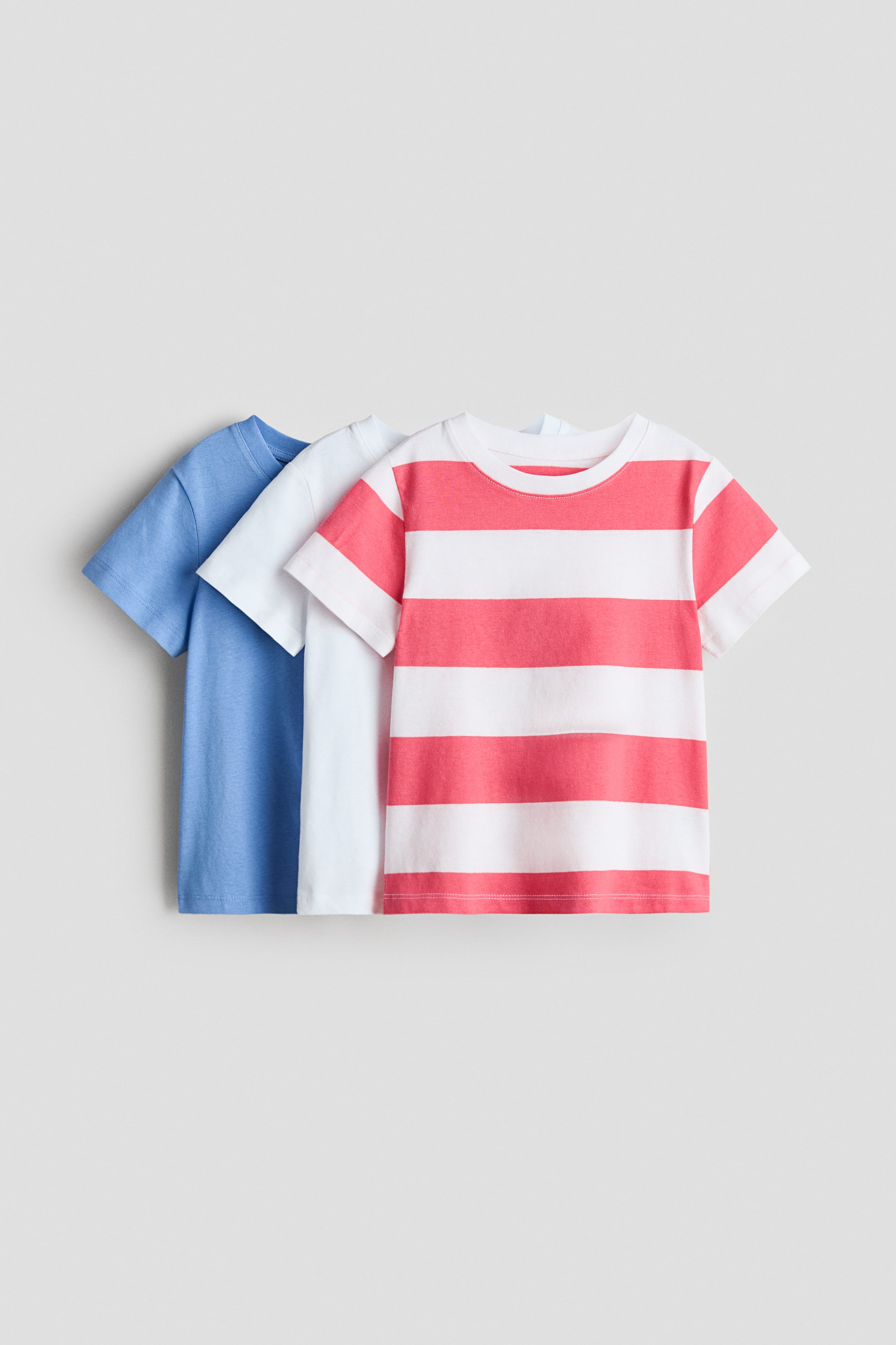 Größeres Bild anzeigen: Drei kurzärmelige T-Shirts aus weichem Baumwolljersey mit einem runden, gerippten Ausschnitt. Die Shirts sind in Hellblau, Weiß und eines mit rot-weißen horizontalen Streifen vorne zu sehen.