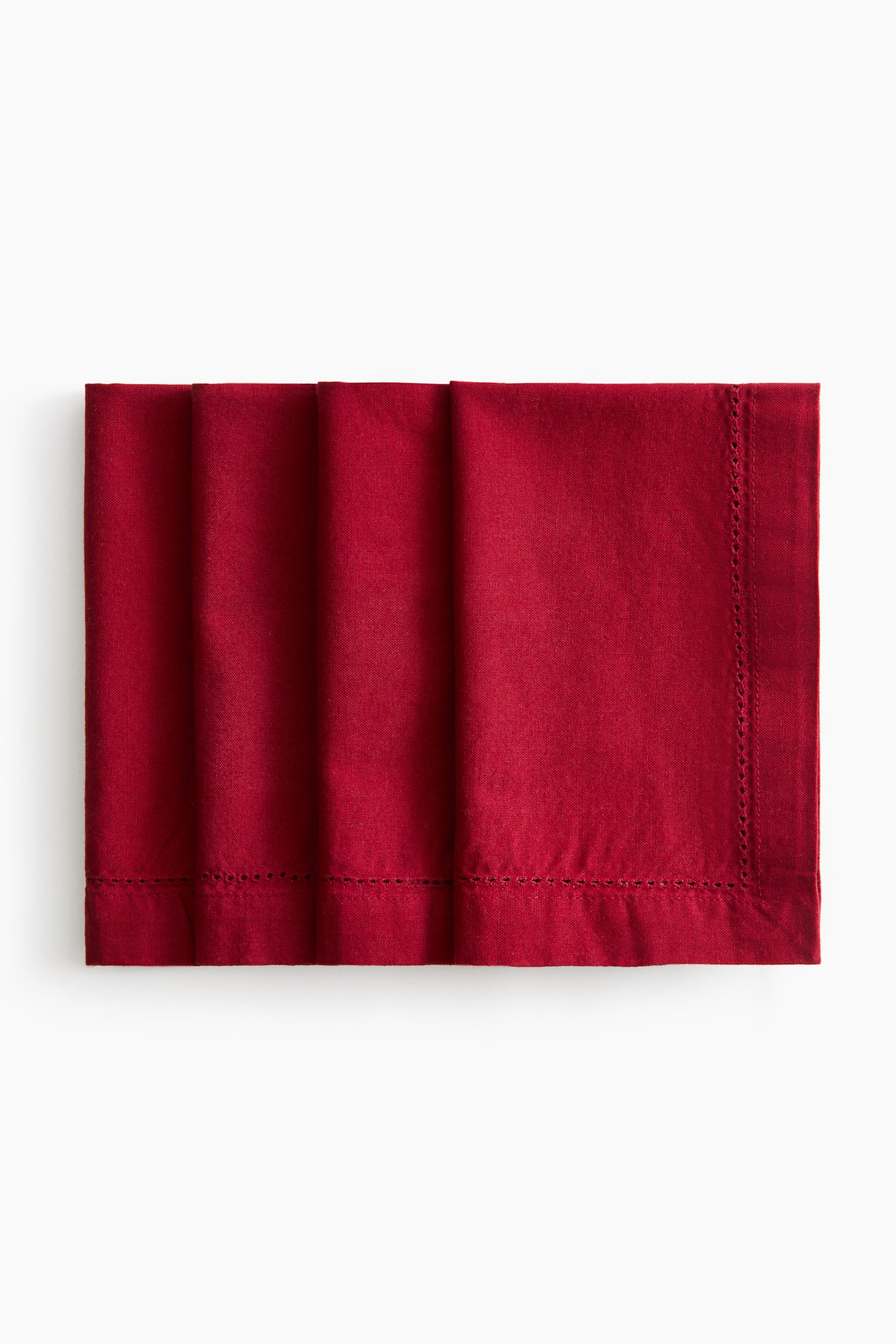 Four dark red cotton canvas napkins are overlapping in a horizontal row, displaying their folded structure from a front view. Each napkin is detailed with a decorative hemstitching border running along a wide, finished hem.