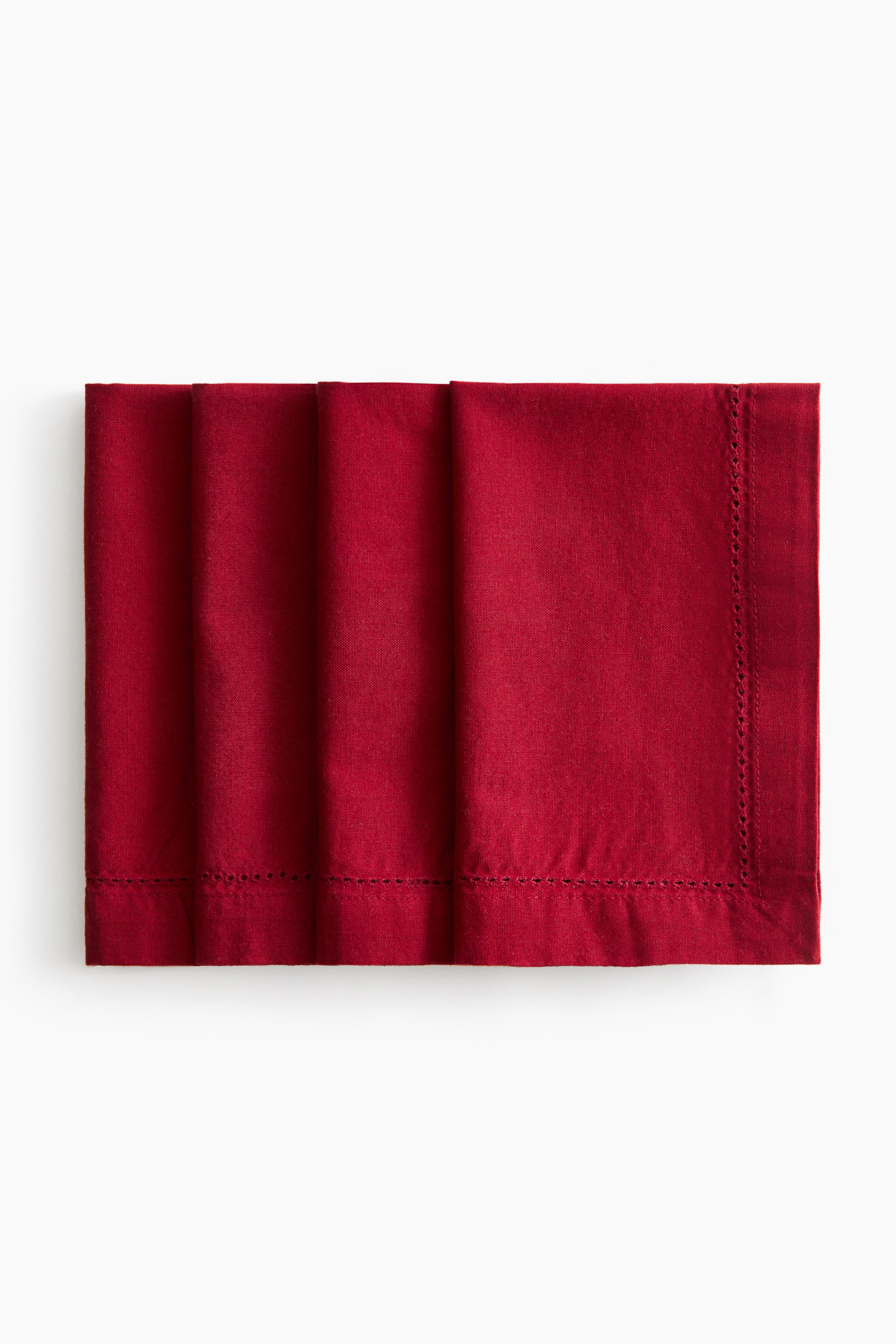 View larger image: Four dark red cotton canvas napkins are overlapping in a horizontal row, showing their folded structure from a front view. Each napkin is detailed with a decorative hemstitching border running along a wide, finished hem.