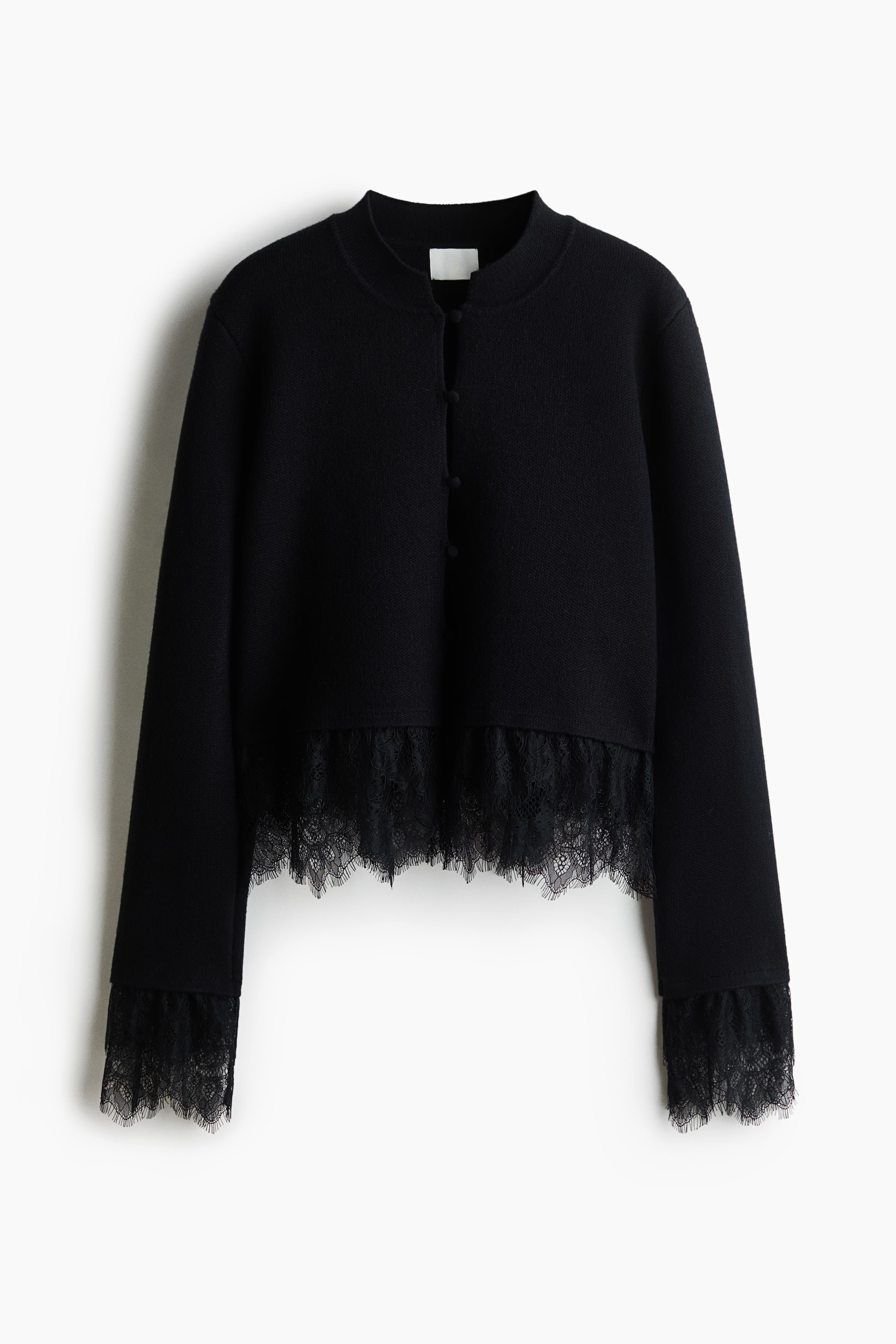View larger image: A black knit cardigan, shown from the front, features a high round neckline and front button closure. Delicate, semi-sheer black eyelash lace trims the cropped hemline and sleeve cuffs.