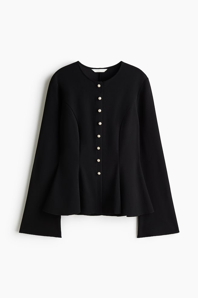 A black peplum jacket is facing front, showcasing a collarless round neckline and a front closure with eight white pearl buttons. The garment is featuring structured vertical seams flaring into a peplum hem and long sleeves widening slightly at the cuffs. - 1
