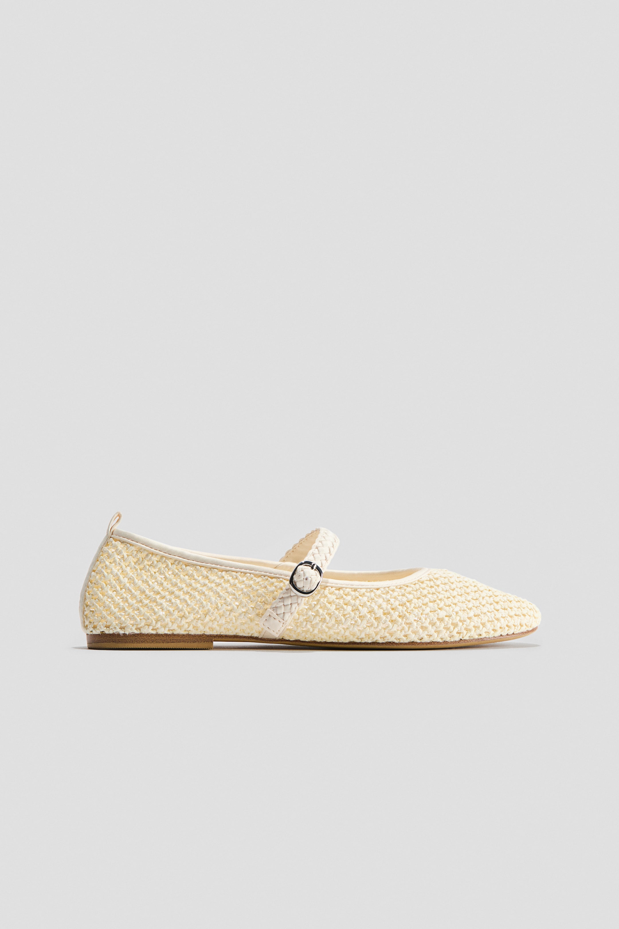 Voir une image plus grande: Une chaussure plate de style Mary Jane présente une tige tissée de couleur crème pâle avec un bout pointu. Elle est dotée d'une bride tissée assortie sur le cou-de-pied, fixée par une petite boucle ronde.