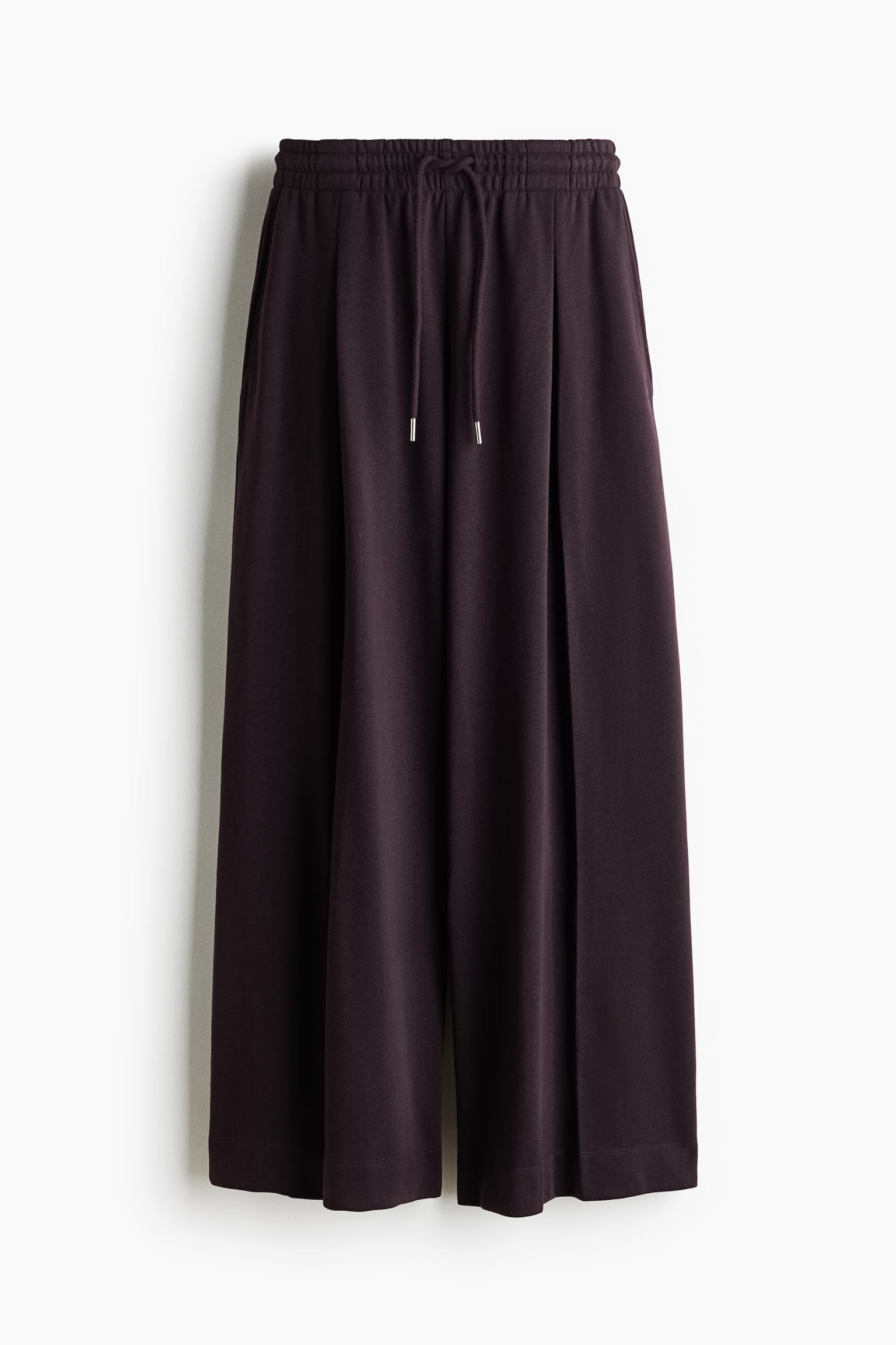 Pantalons à coupe ample en tissu de sweat léger présentés de face, avec une taille élastiquée à cordon de serrage et des jambes extra-longues et larges avec un pli creux inversé à l'avant.