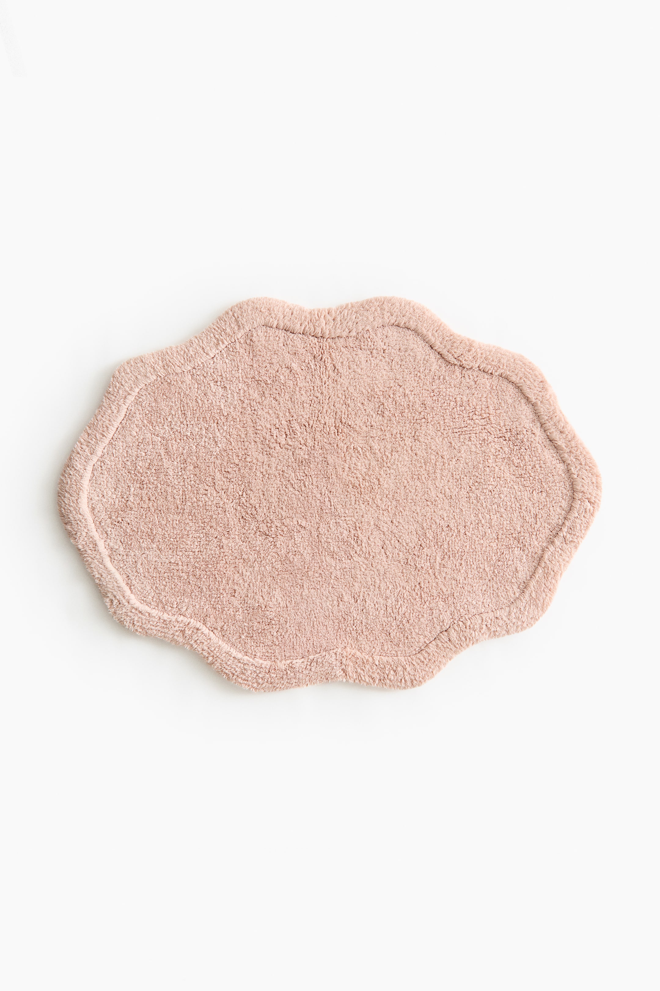 View larger image: A bath mat featuring a tufted cotton texture in a soft light pink shade. It showcases an art deco-inspired silhouette with a distinct raised border.