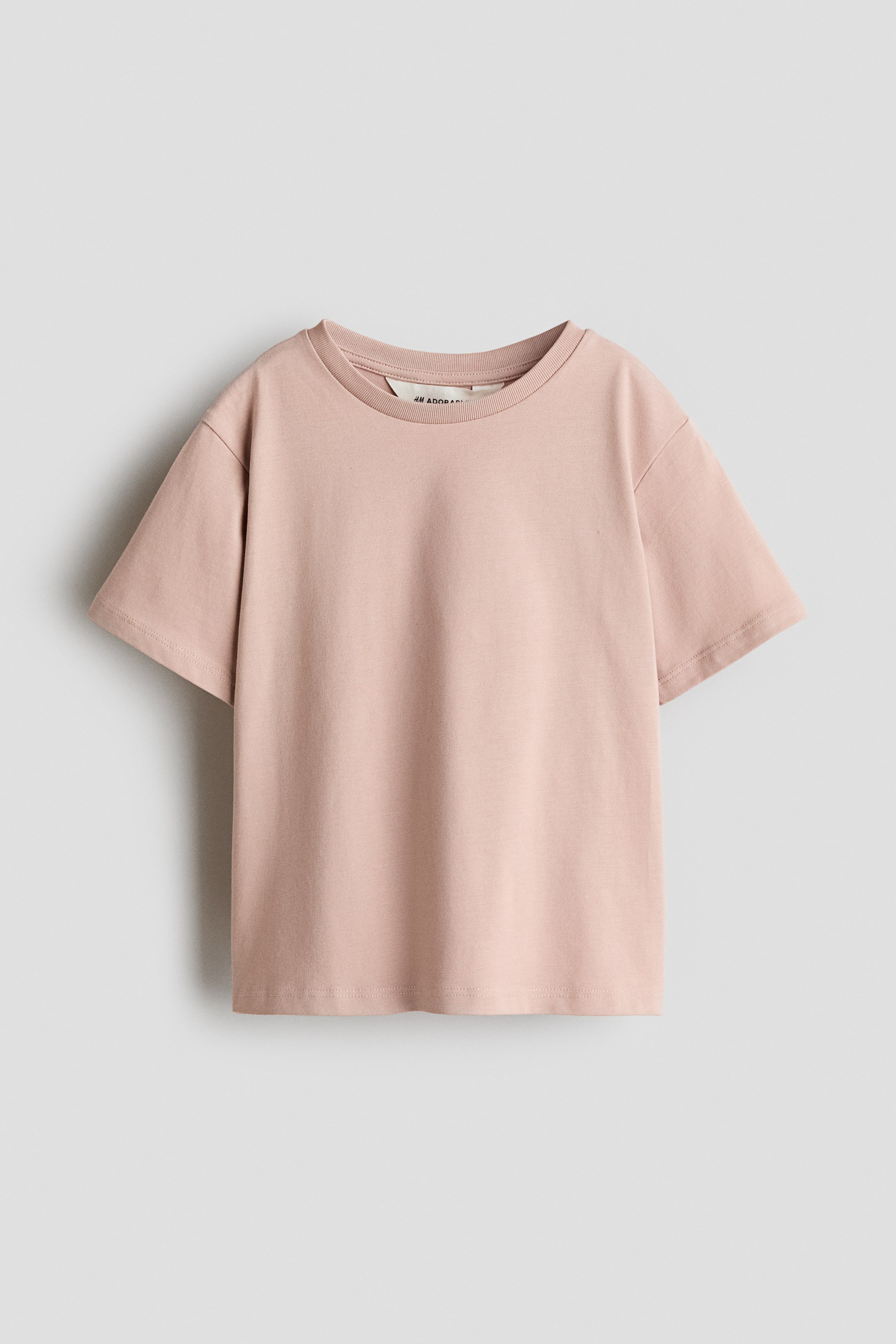 View larger image: A light pink loose-fit T-shirt is displayed from the FRONT, featuring a round, rib-trimmed neckline, dropped shoulders, and short sleeves. The smooth jersey fabric drapes softly.