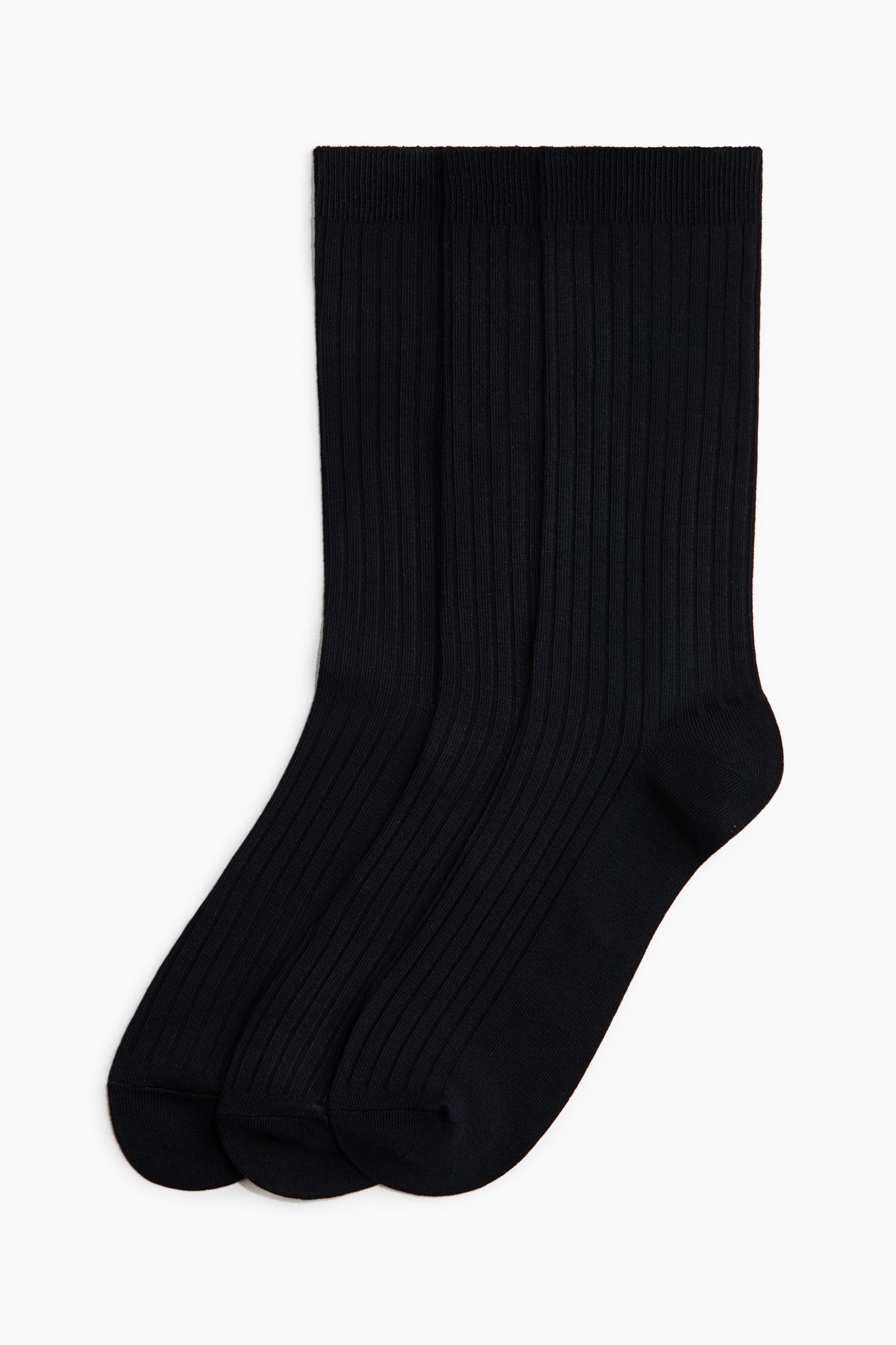 View larger image: Three black socks are displayed with a ribbed texture along the leg. Each sock features a defined cuff, heel, and toe, and they slightly overlap with their fronts facing forward.