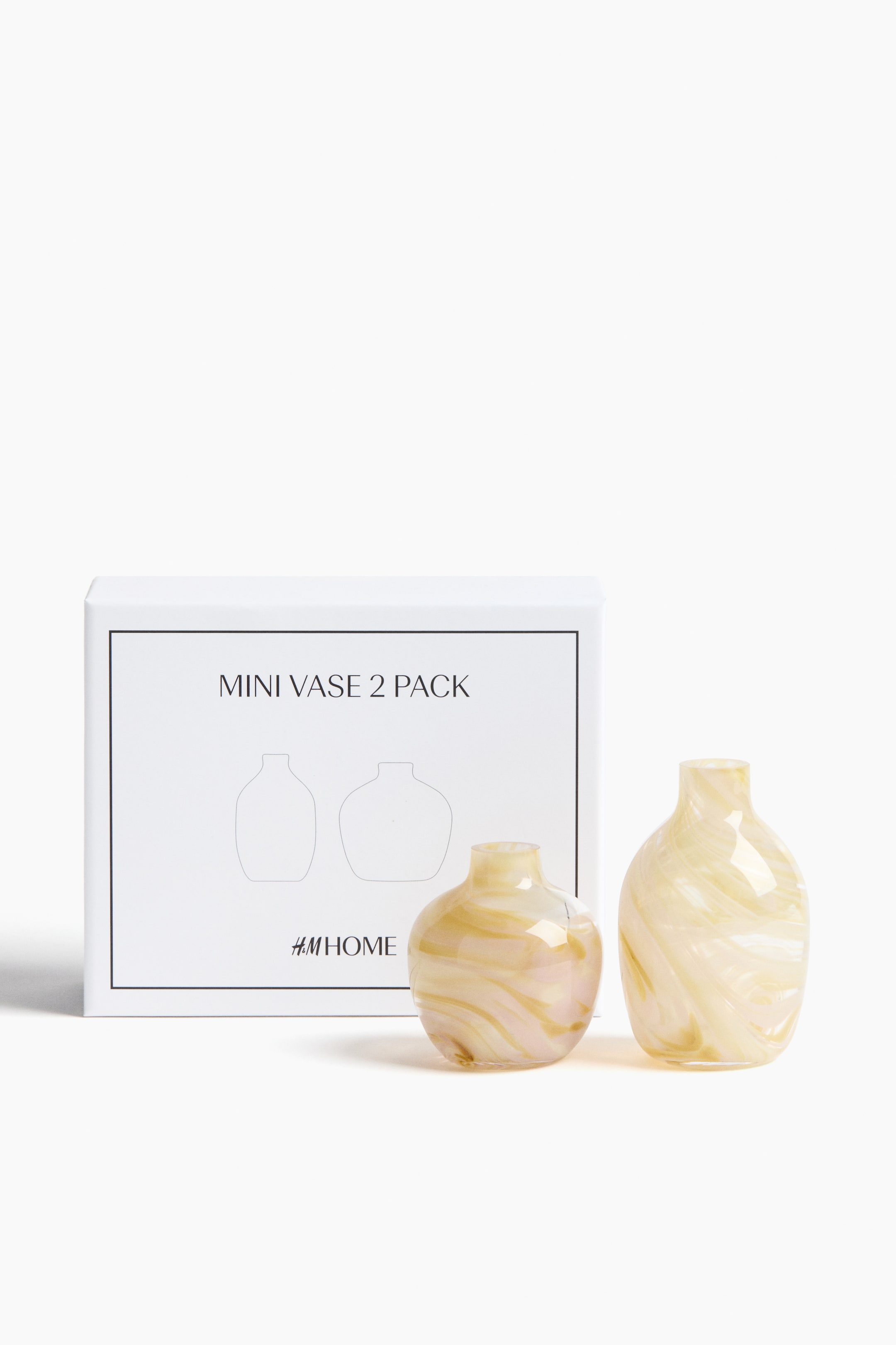 Zobacz większy obraz: Mini Vase 2 Pack prezentuje dwa niewielkie, półprzezroczyste szklane wazoniki, każdy z przeplatającymi się kremowo-białymi i bursztynowymi wzorami oraz wąskimi otworami. Jeden wazon ma krótszą, zaokrągloną formę, natomiast drugi — wyższą, wydłużoną sylwetkę; oba ustawione są przed białym pudełkiem.