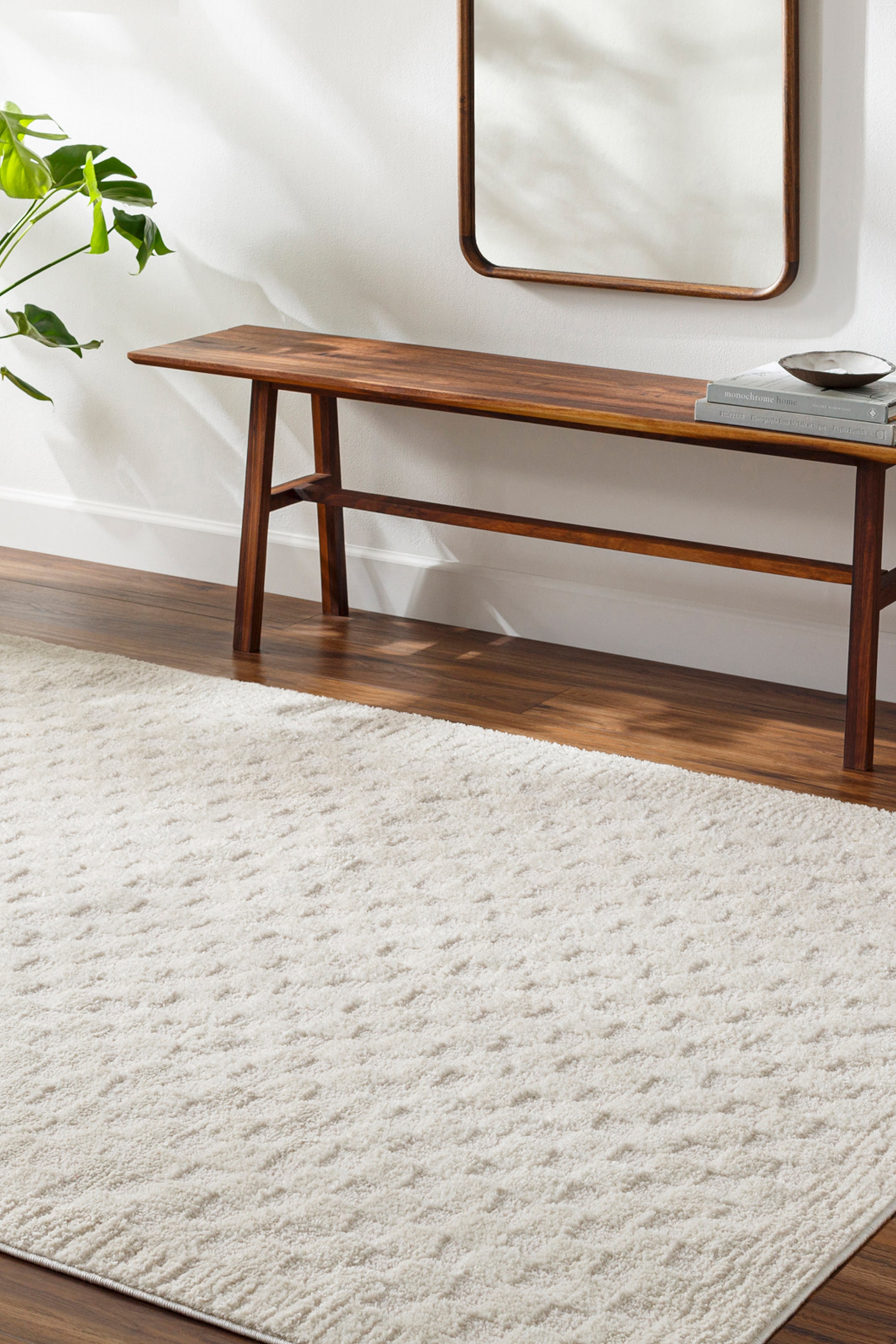 View larger image: A rectangular cream-coloured rug is laid flat, displaying a subtle textured pattern of raised geometric shapes across its surface.