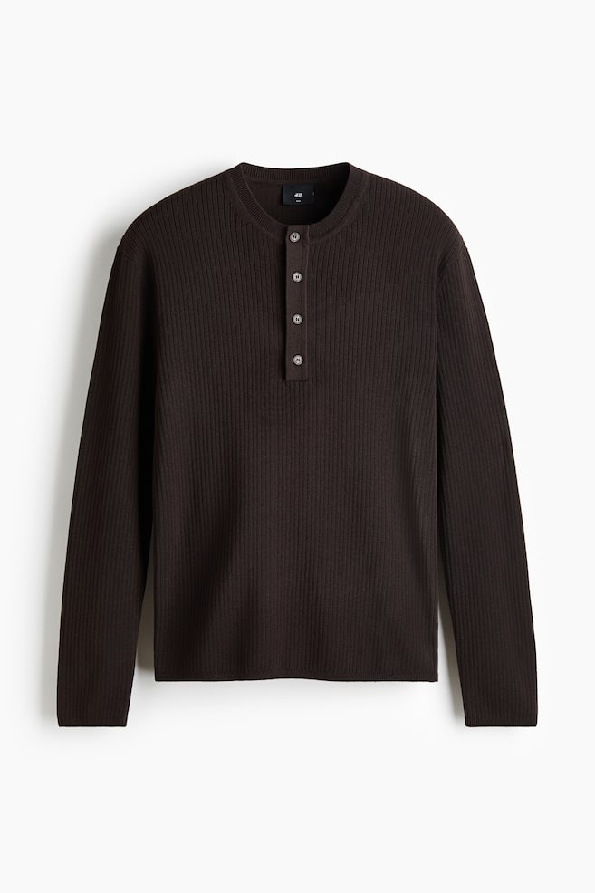 A dark brown long-sleeved henley shirt is shown from the front, highlighting a ribbed knit texture throughout the body and sleeves. It features a round neckline leading to a four-button placket with dark, round buttons. The long sleeves end in finished cuffs, and the bottom hem is also neatly finished. - 1