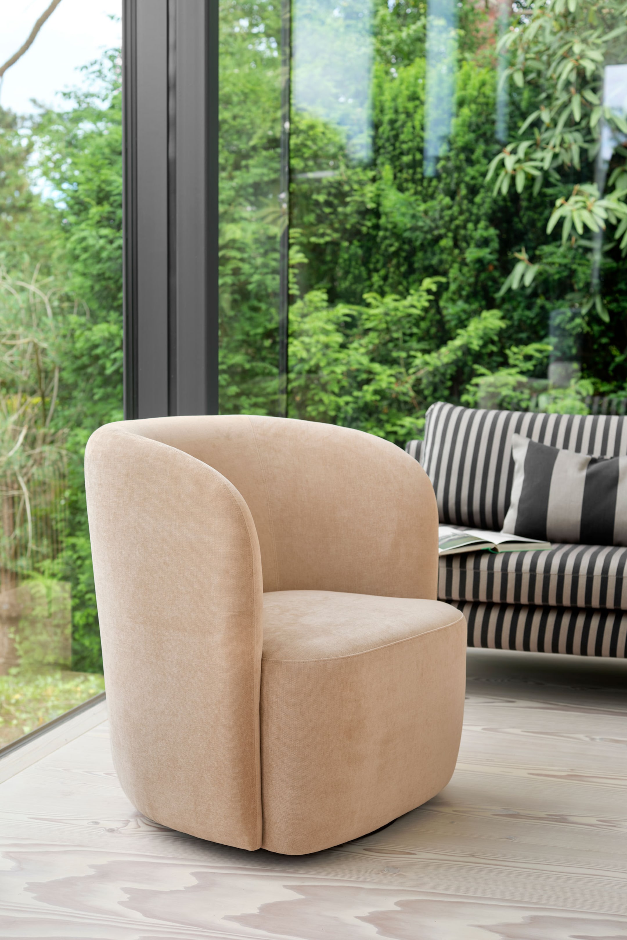 Agrandir l'image: Un fauteuil crapaud beige, revêtu de velours, est présenté en angle trois quarts vers la droite, mettant en valeur son dossier courbé et enveloppant ainsi que son assise épaisse et rembourrée. Cette chaise moderne présente une base cylindrique sans couture, habillée du même tissu doux et beige clair.