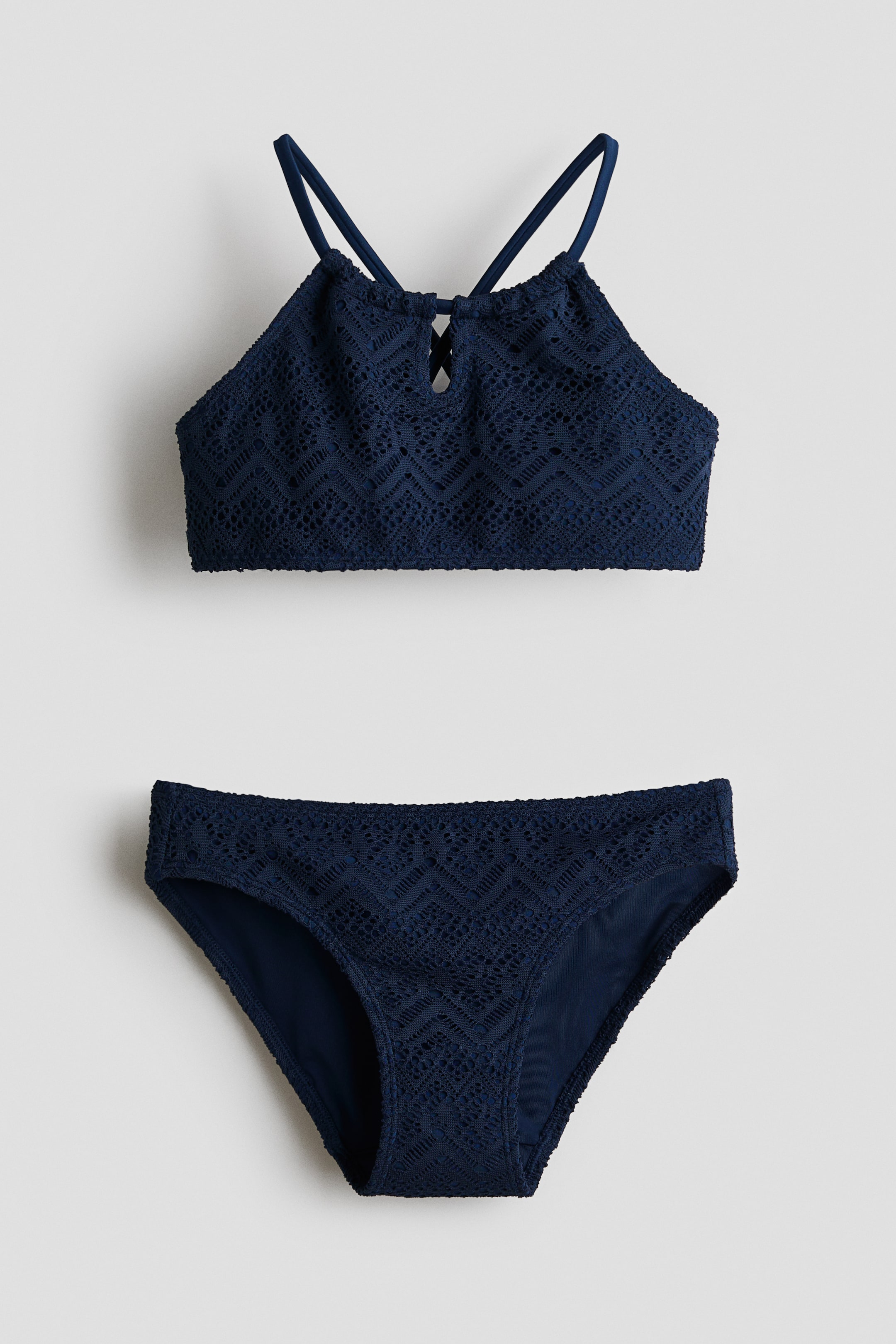 Grotere afbeelding bekijken: Een donkerblauwe bikini met een gehaakt-look over beide delen. Het topje, gezien van voren, heeft een smalle snit met een ronde halslijn, een keyhole-opening aan de voorkant en smalle schouderbandjes die op de rug kruisen. Het broekje is een bijpassend slipje.