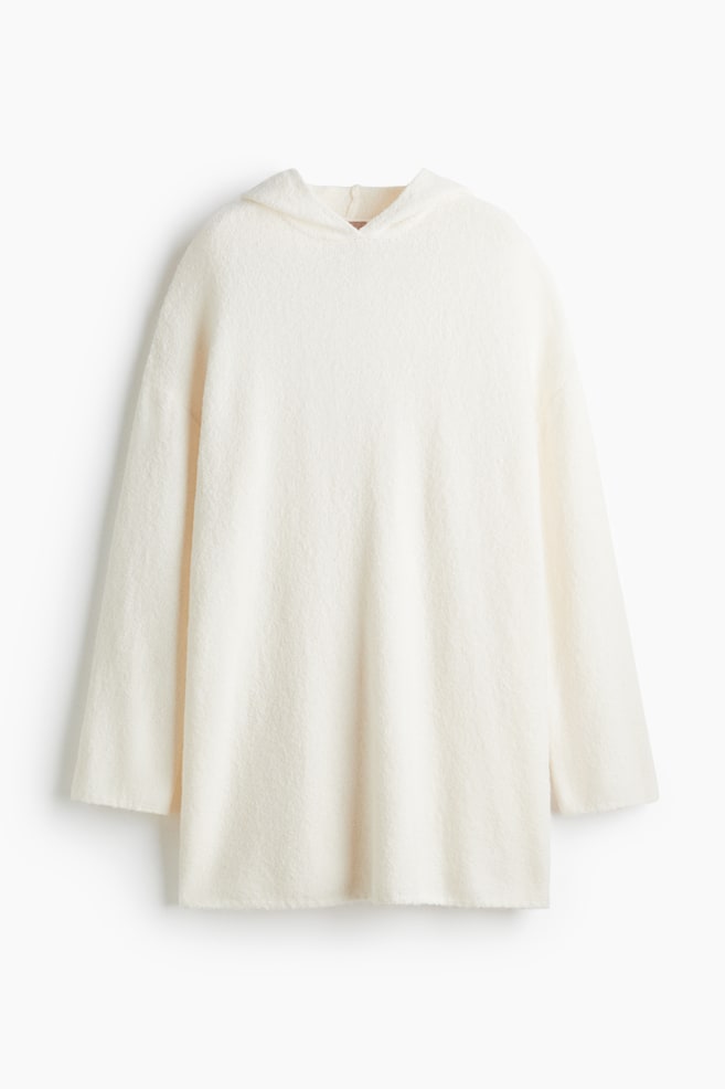 A cream-colored, long-sleeved hoodie is presented from the front, showcasing a relaxed fit. It is featuring a soft, fuzzy texture and an unfinished hemline. - 1