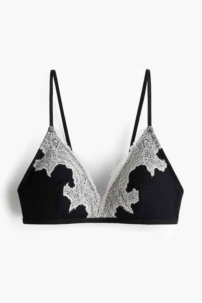 A black ribbed bralette displays its front, featuring triangle cups. Light-coloured lace with intricate floral patterns and scalloped edges overlays the cups. - 1