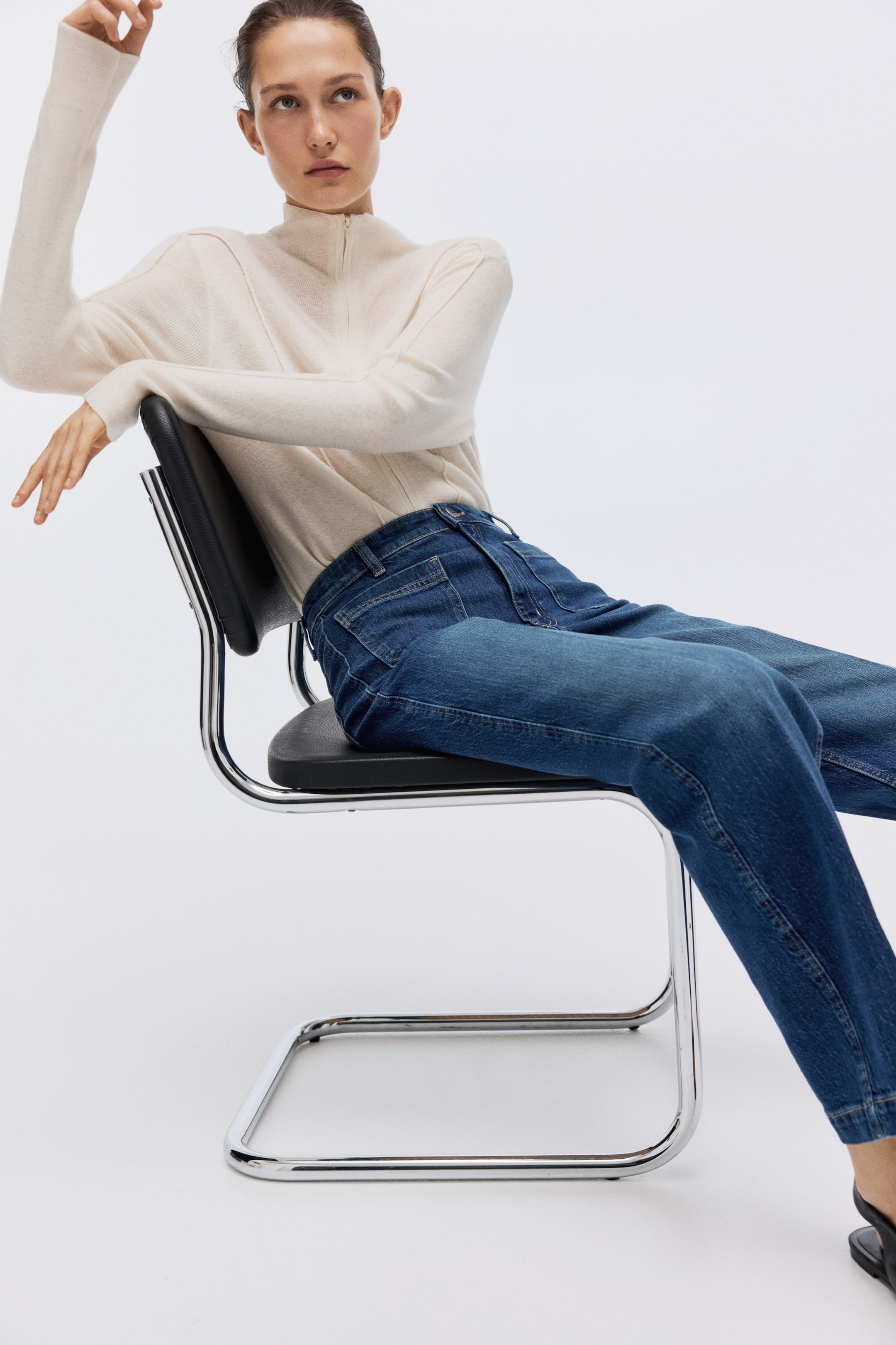 View larger image: The dark blue denim jeans feature a relaxed fit that tapers towards the ankle. Shown from a slightly elevated side angle, they display standard five-pocket styling with belt loops and visible seam detailing.