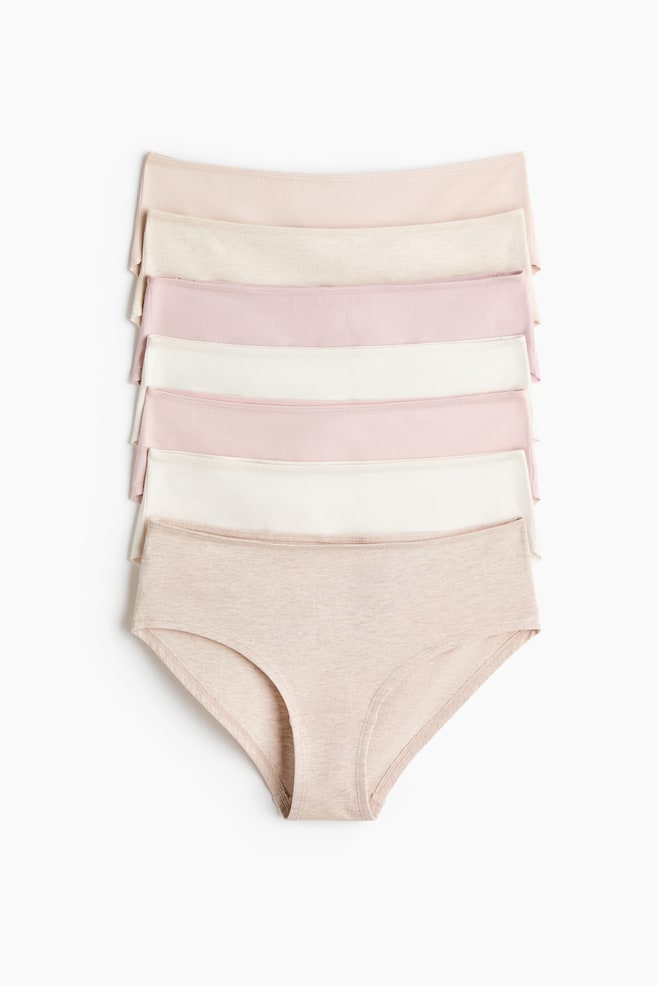 Briefs in jersey with a mid waist, lined gusset, and medium coverage at the back are stacking in various neutral and pastel colors. The bottom brief is facing front, displaying its front cut and leg openings. - 1